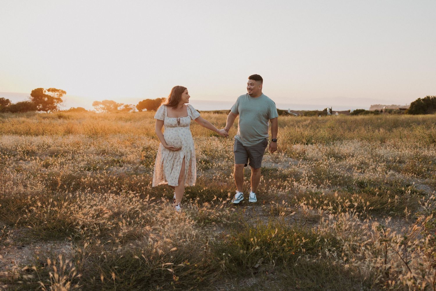 Sunset maternity photo in a field with golden light illuminating the scenic landscape.