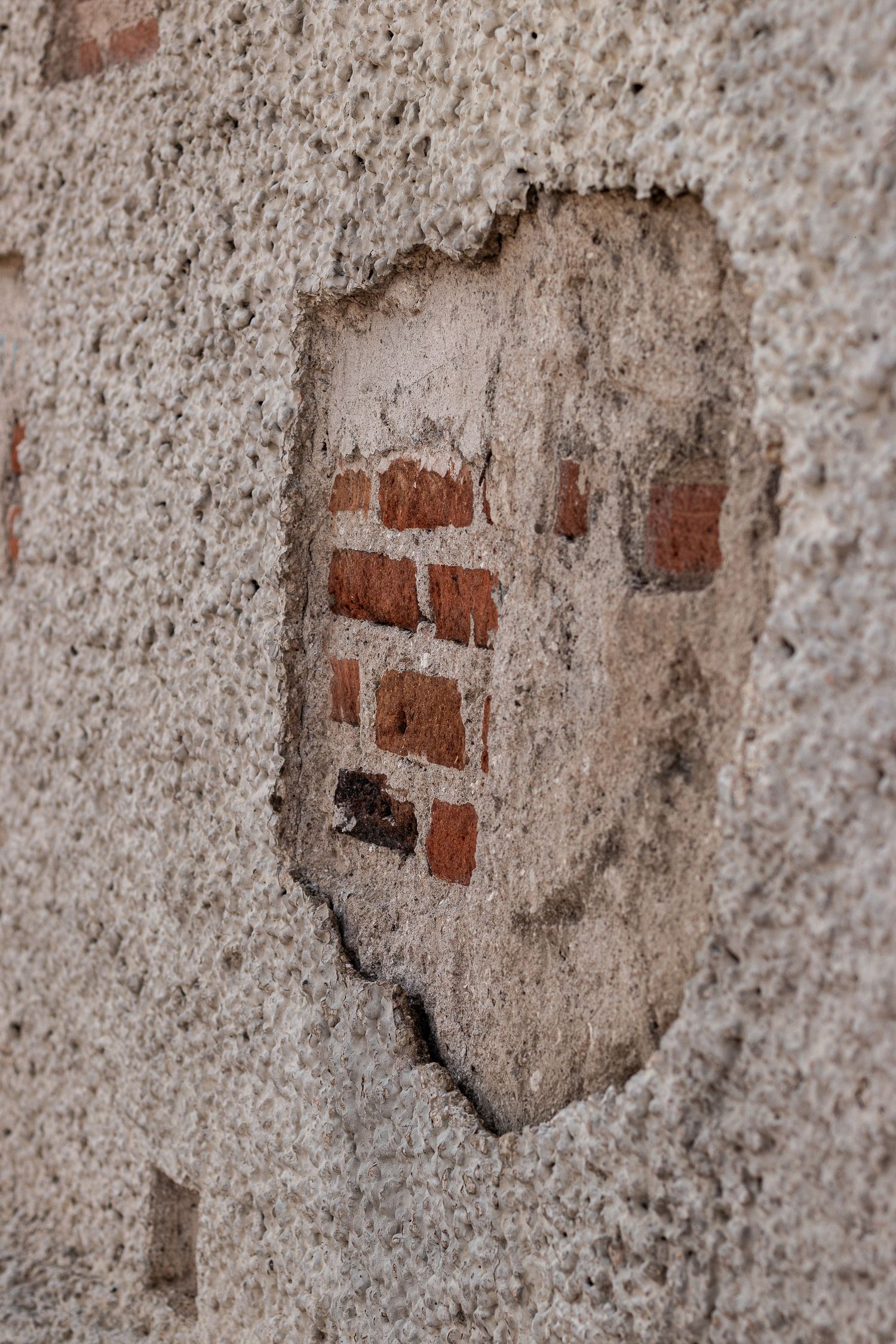 Close-up sequence of weathered concrete wall showing exposed brick pattern in a deteriorating circular shape.