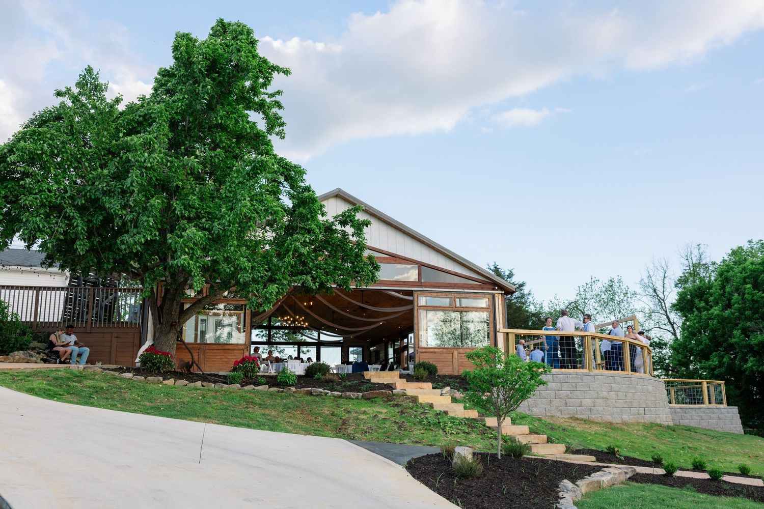 A panoramic view of a residential backyard with lush green trees and landscaping on a sloping terrain.