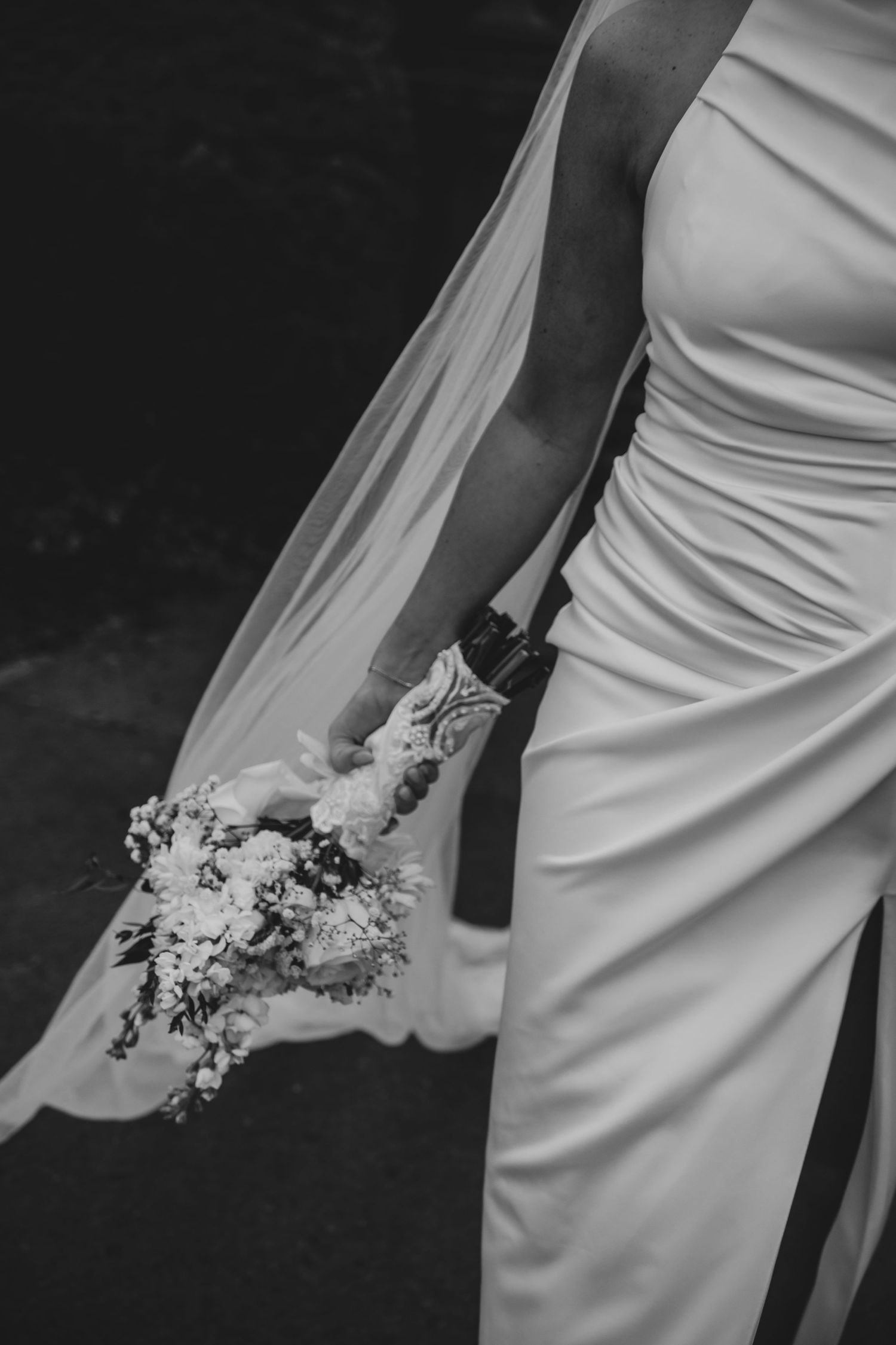 Newlywed couple walks down a city street in formal wedding attire on their special day.