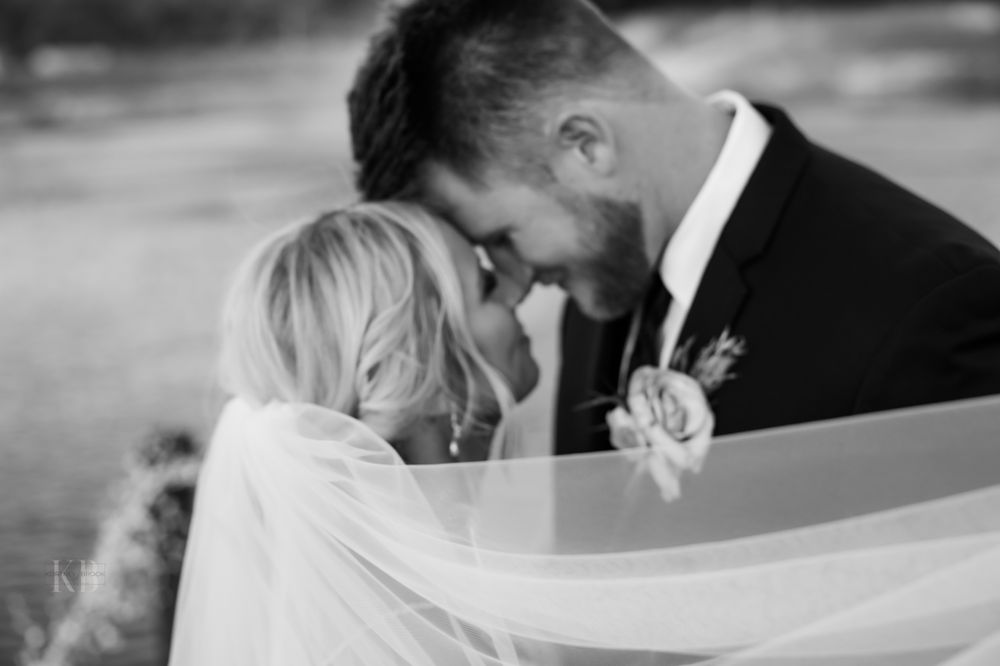 Black and white intimate wedding moment captured through flowing veil.
