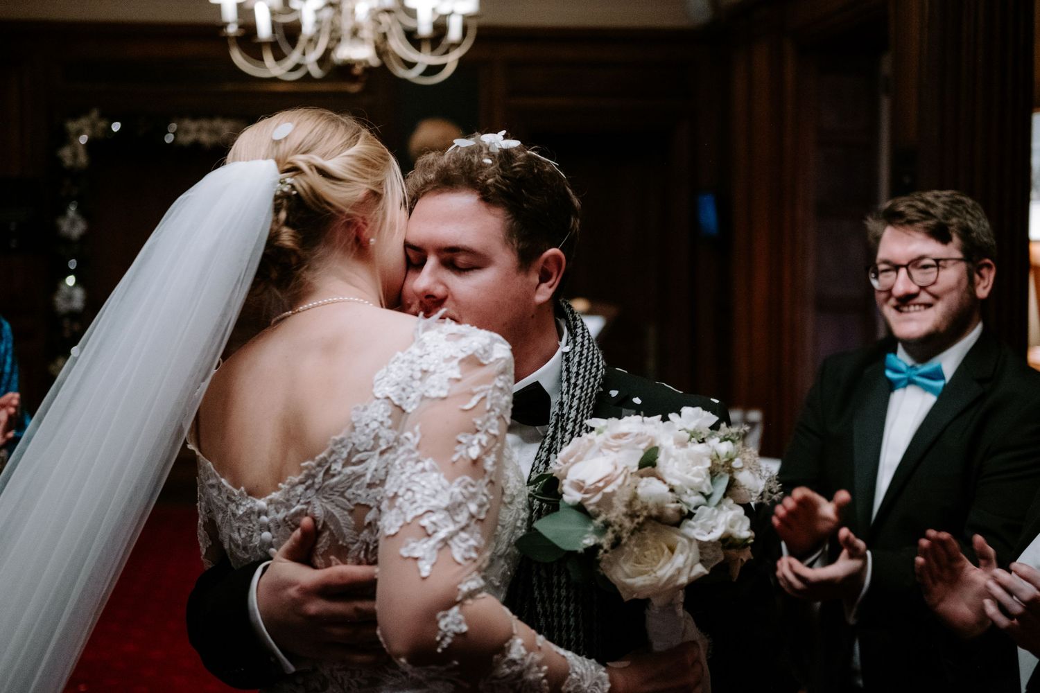 Elegant wedding reception scene with crystal chandelier and formal attire.