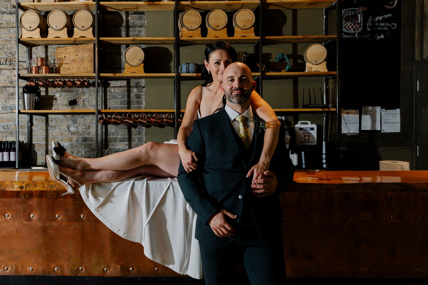 Romantic couple posing in a rustic bar with wooden barrel decor.