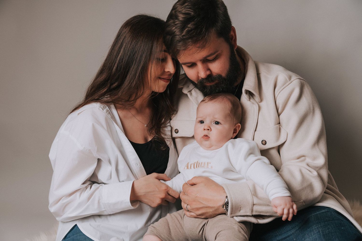 Portrait series showing tender family moments against a neutral background.