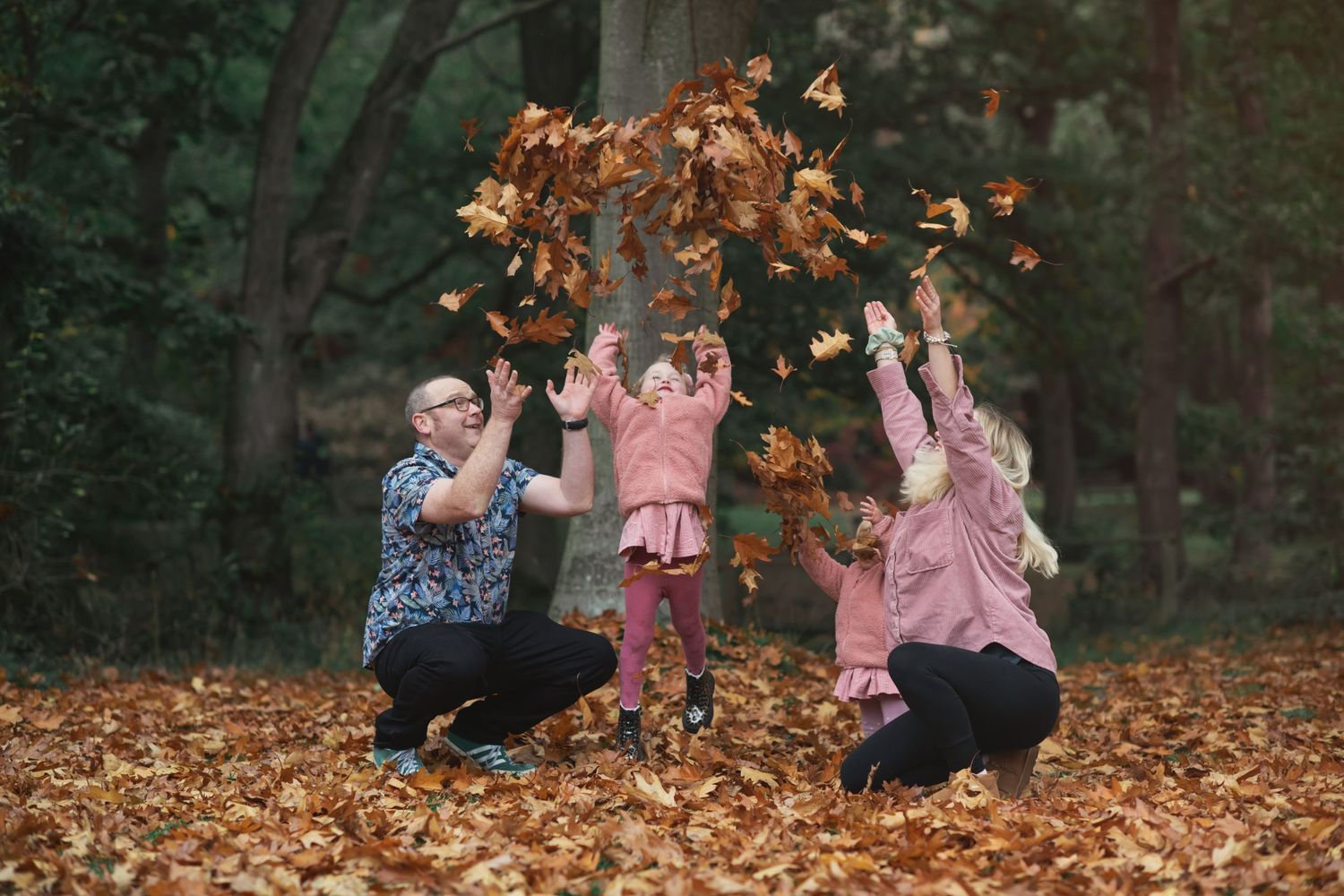 A family throwing Autumn leaves into the air together