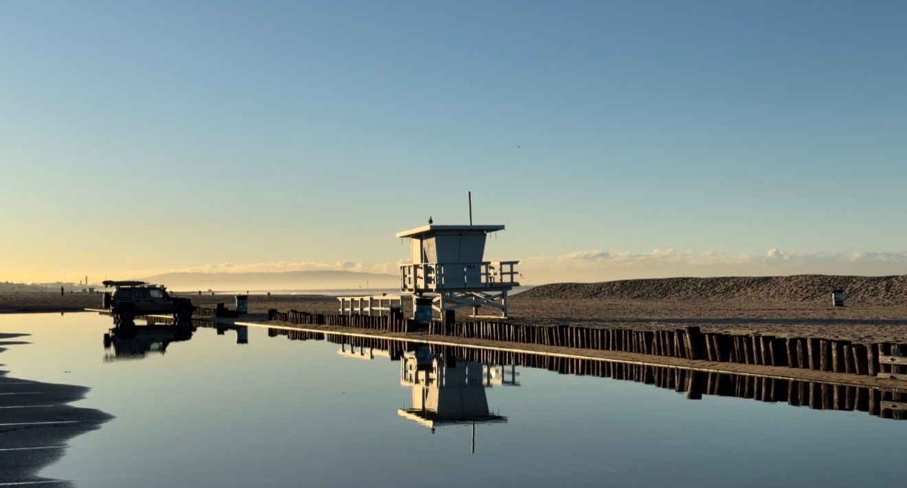 A scenic panoramic view of a marina with boats docked along wooden piers stretching into calm blue waters at sunset.