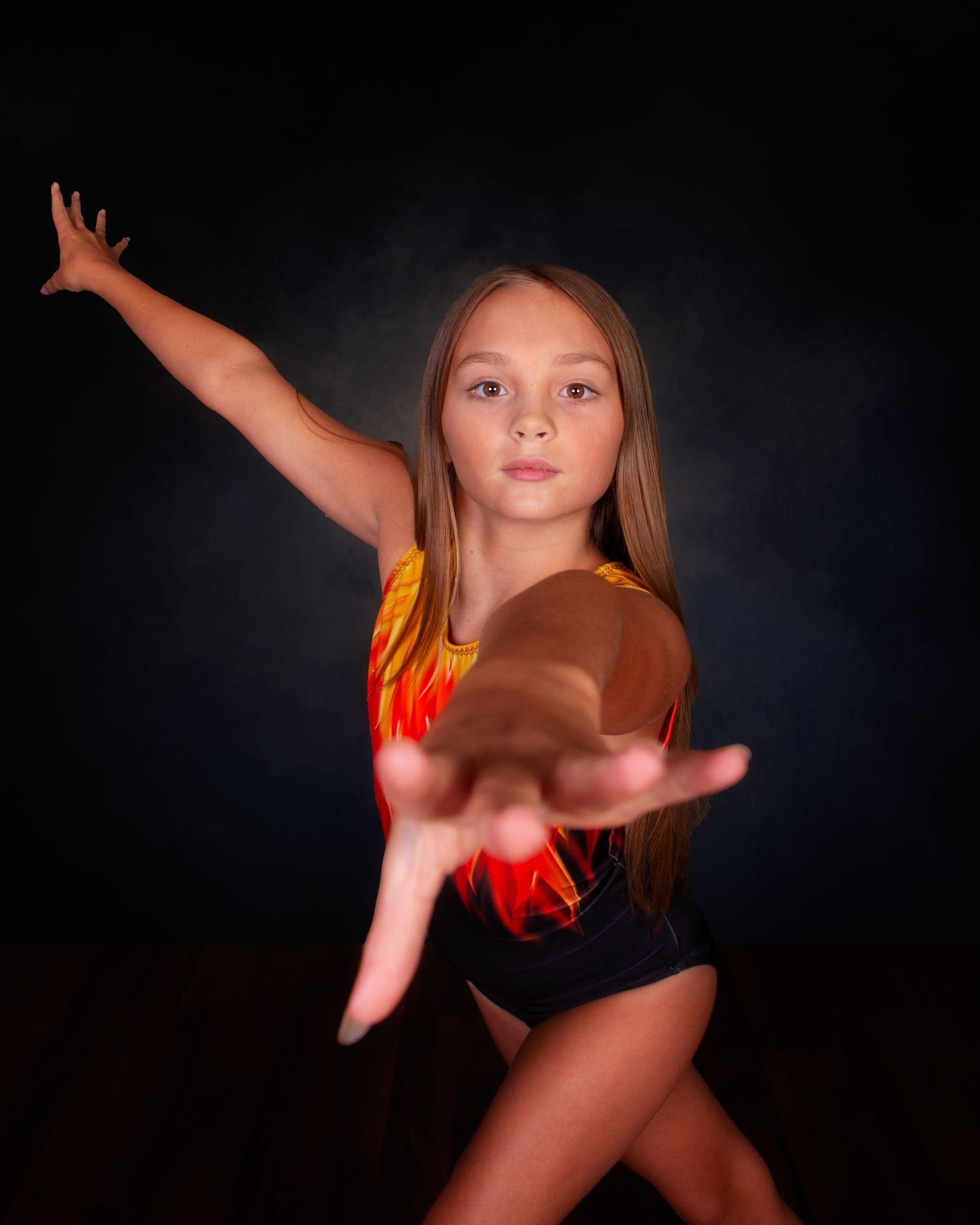 Two gymnasts in navy leotards pose back-to-back in dramatic lighting against a dark background.