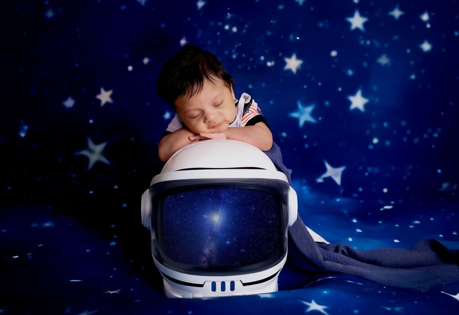 A series of seven photos showing a baby sleeping in a blue astronaut helmet against a starry background.