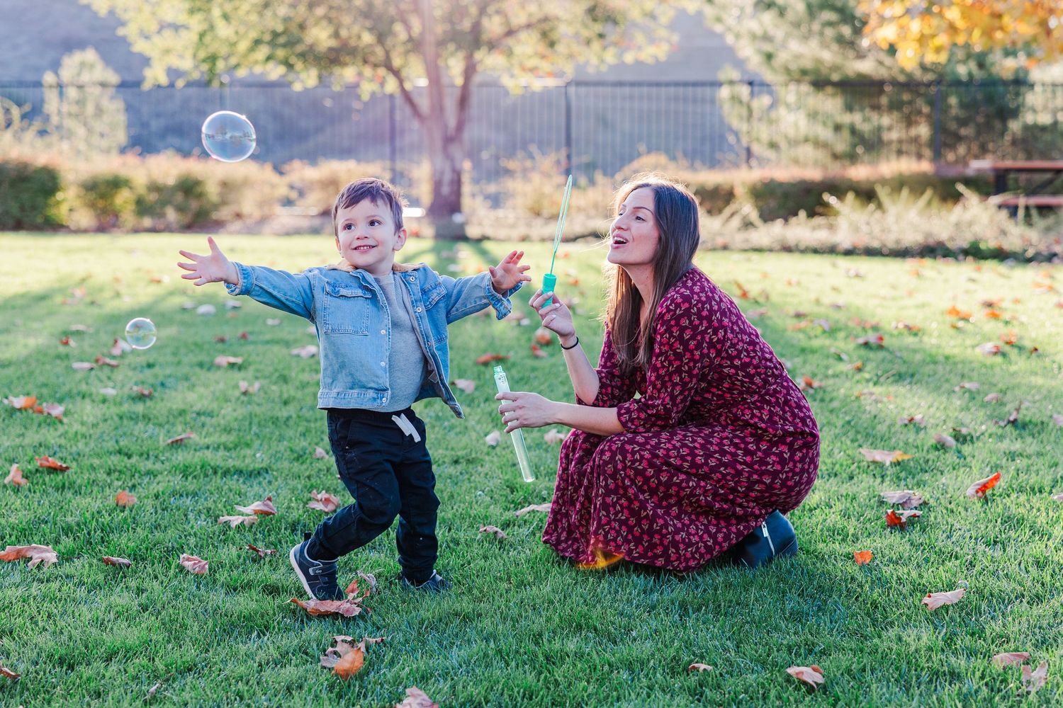 A playful scene of blowing bubbles on a grassy lawn during a sunny autumn day.