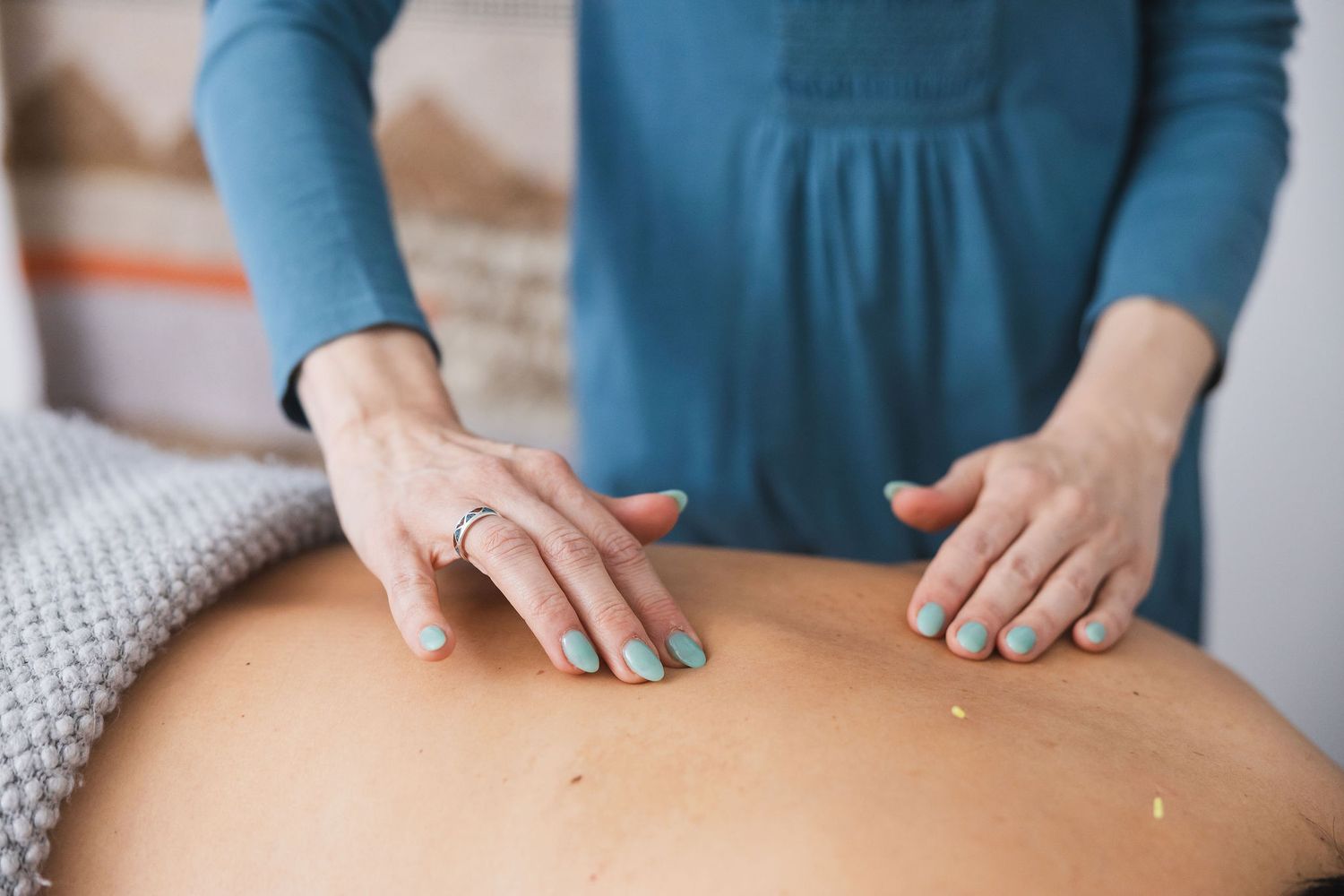 Maple Valley Acupuncture, WA branding photo of woman's hands on bare back of female client feeling points to insert needle