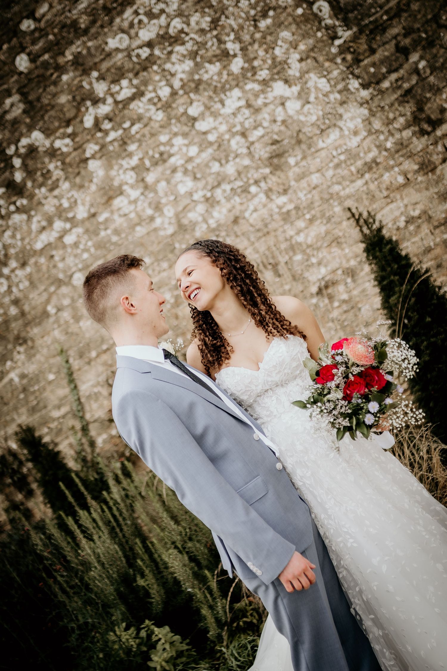 A romantic wedding couple dips and embraces on a green lawn in a joyful dance pose.
