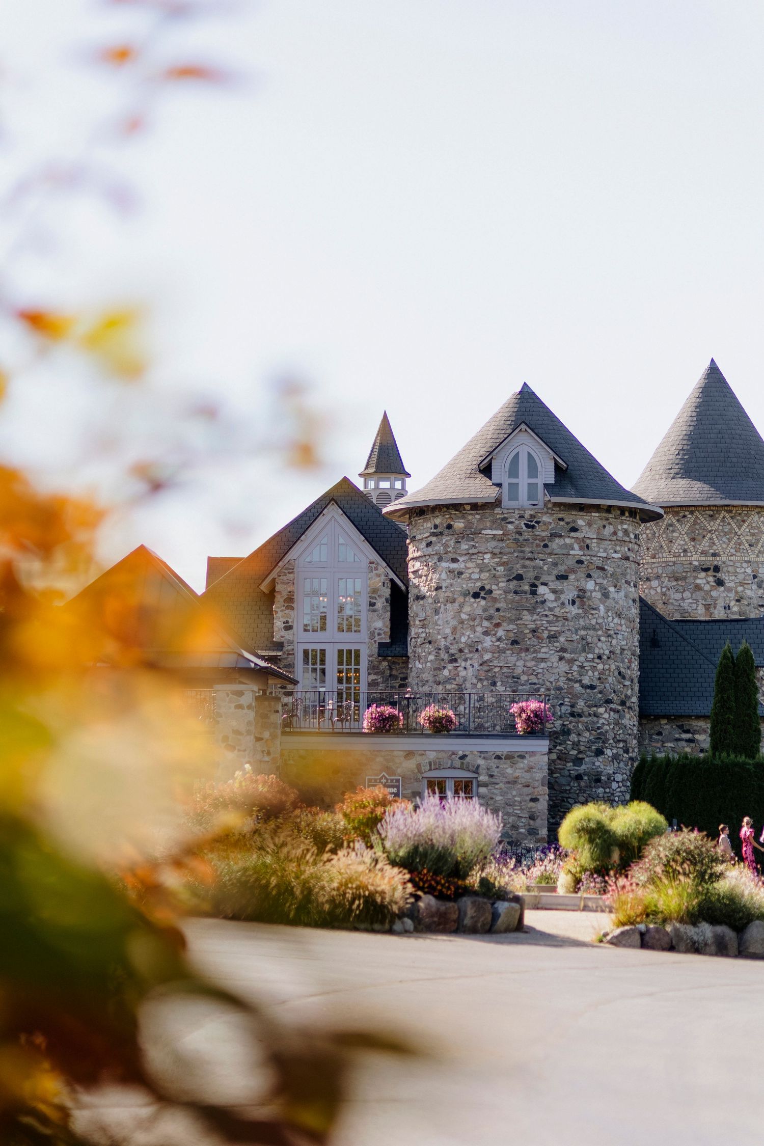 Stone castle venue with turrets and windows captured during golden hour with flowers in foreground.