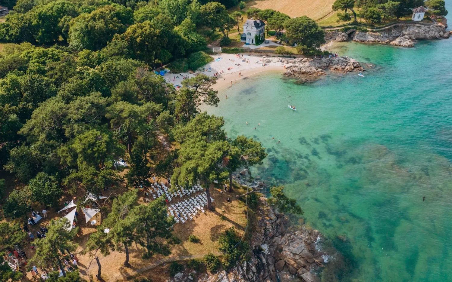 Aerial view of crystal clear turquoise waters and rocky coastline with lush green trees in Hawaii.