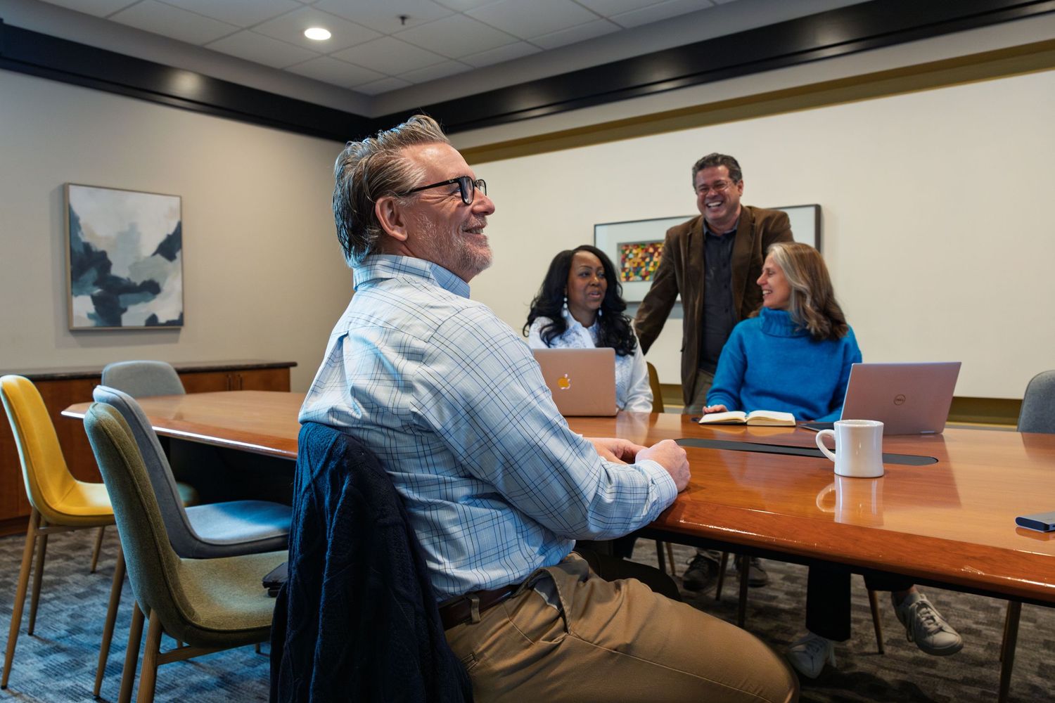 People having a discussion around a conference table in a modern office meeting room.