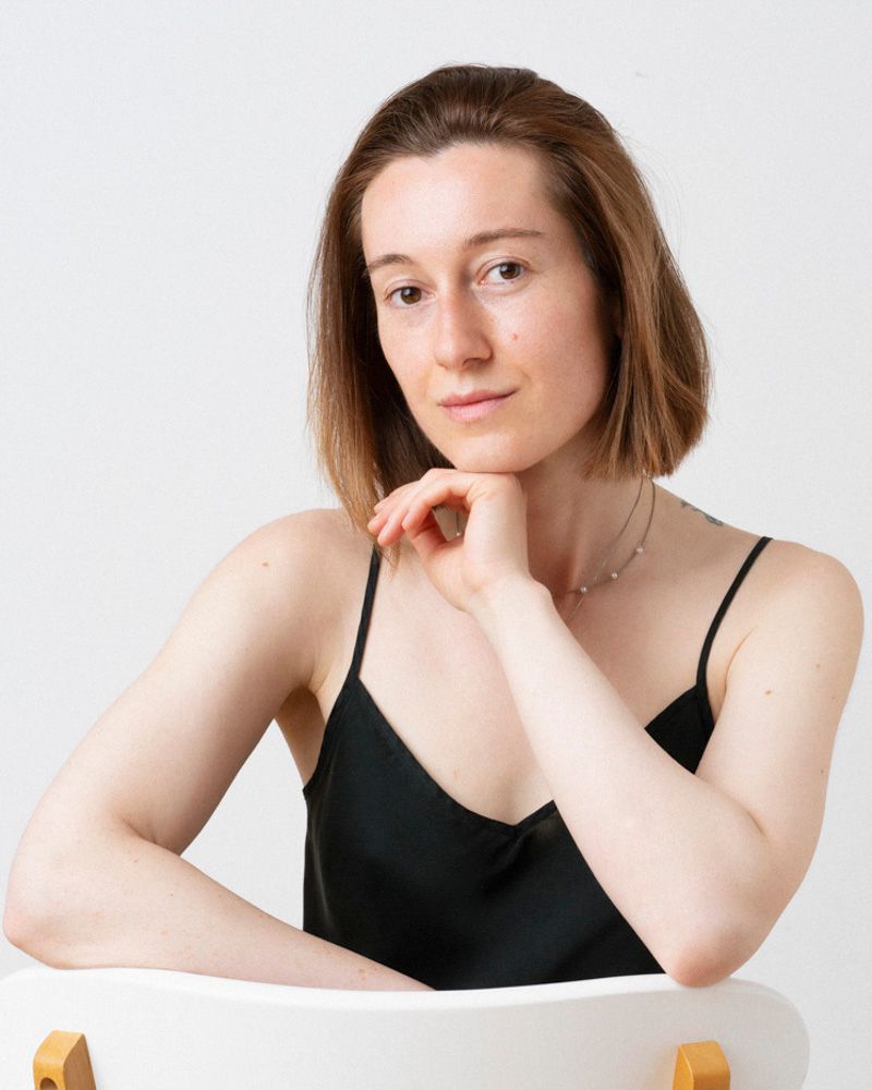 Portret feminin natural realizat in lumina soft, fundal minimalist, expresie autentica si relaxata