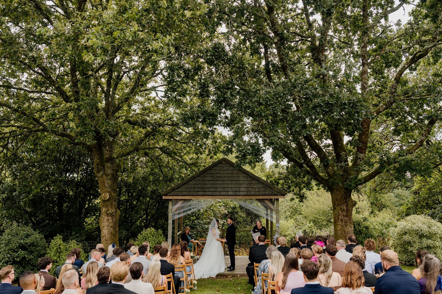 Bride and groom walk through confetti shower in the garden at Kingston Estate in Devon.