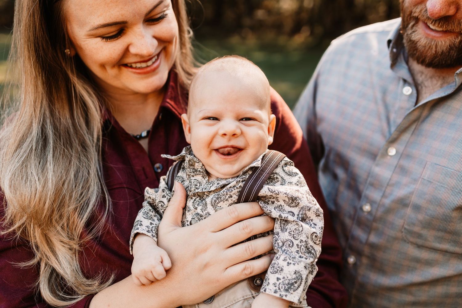 Smiling woman with long hair holds a happy baby during a family photo session in Knoxville, TN.