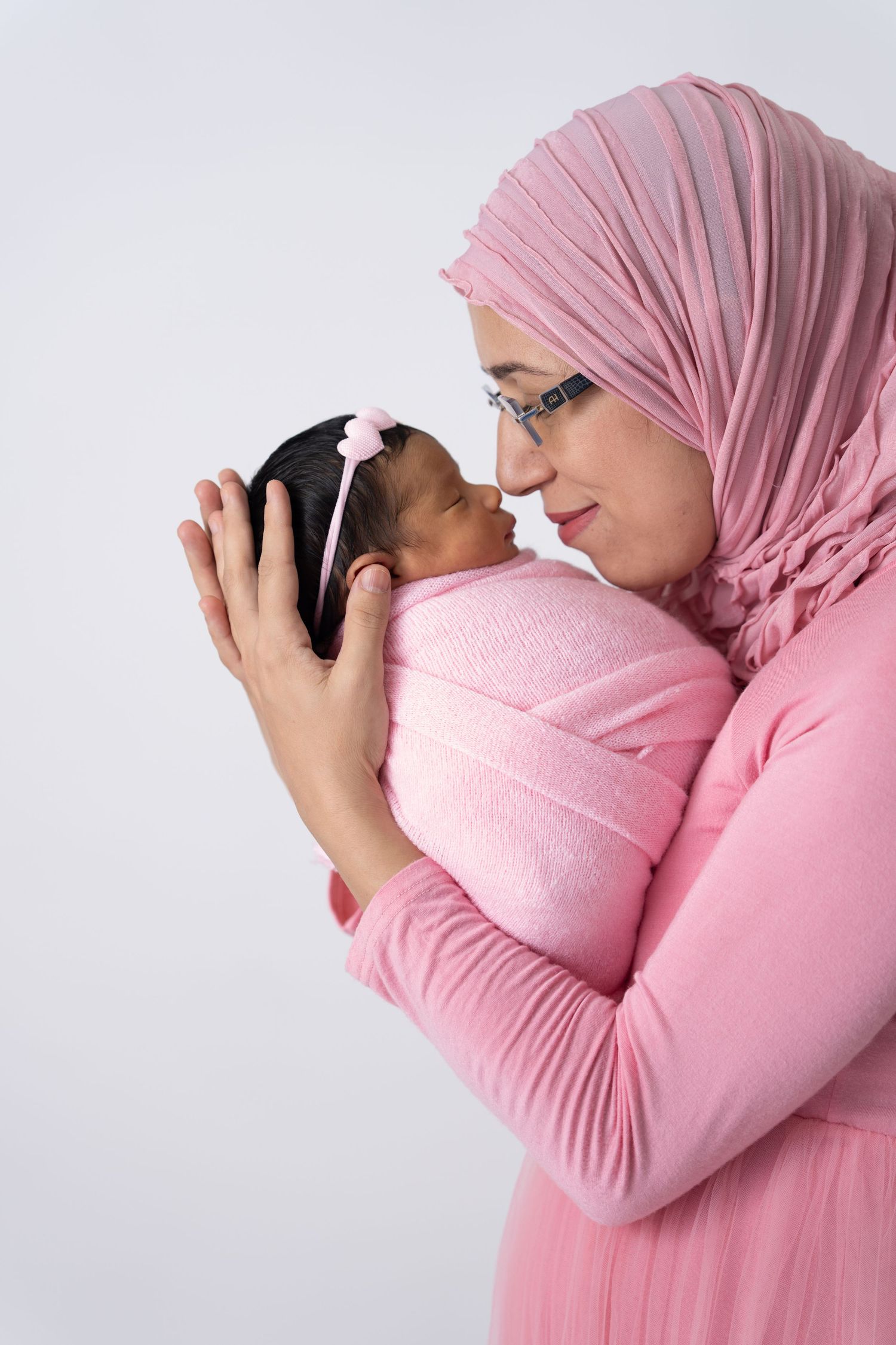Mother and newborn in a calm photoshoot with a new born photographer Dubai, capturing a gentle postpartum moment in a cozy studio
