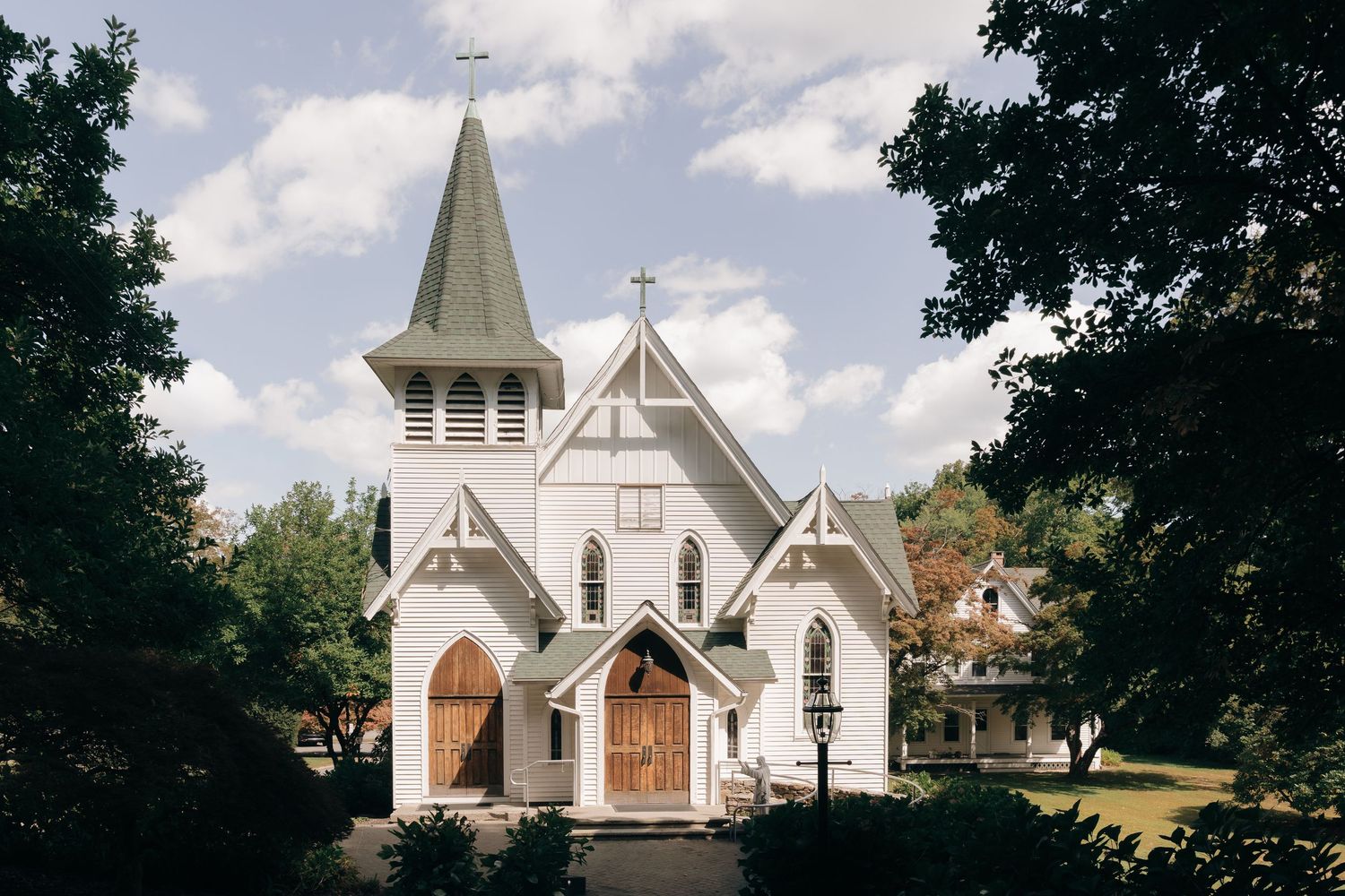 A row of white church steeples and buildings set against a blue sky with trees framing the scene.
