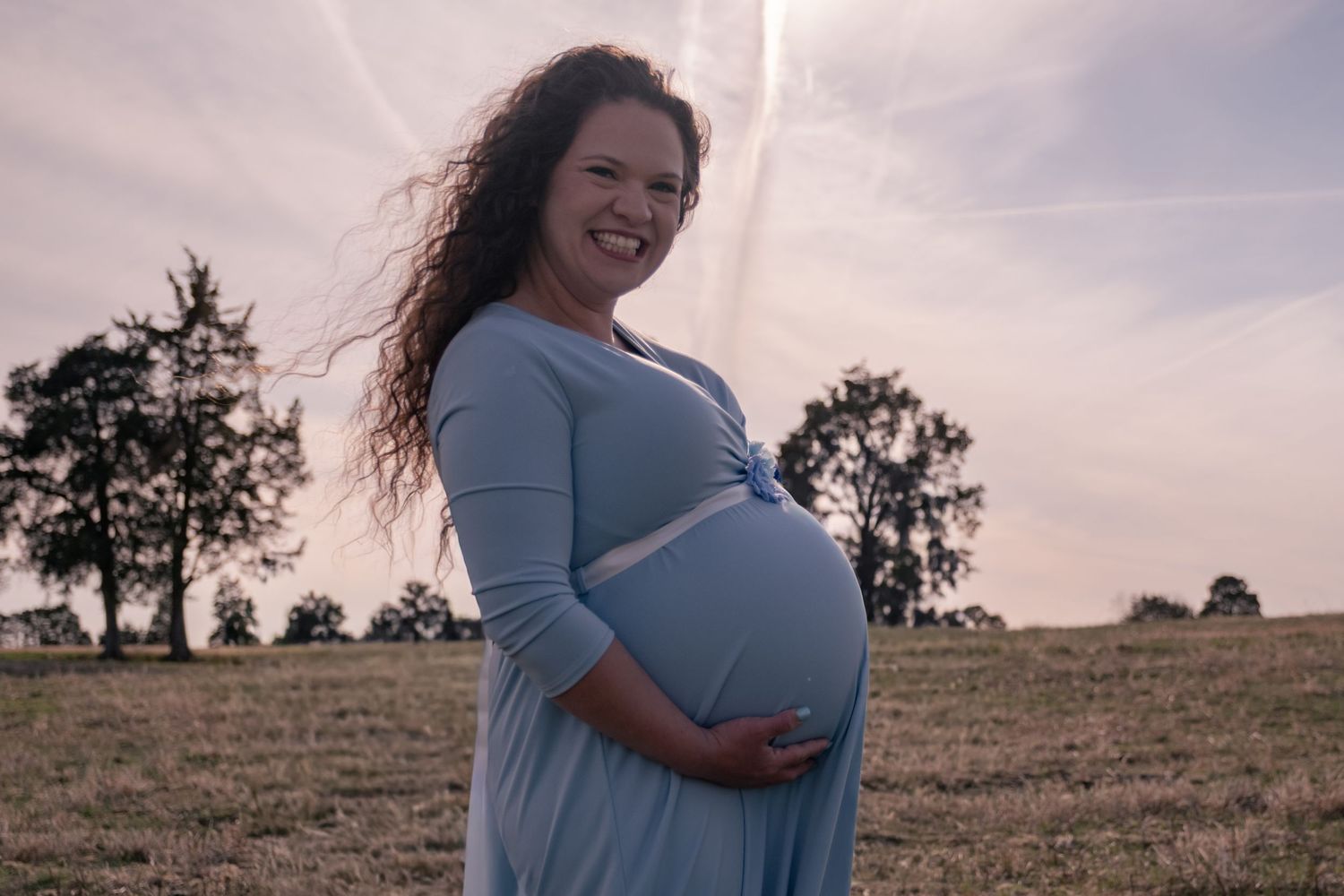 A series of maternity photos showing a pregnant woman in a light blue dress against a sunset sky.