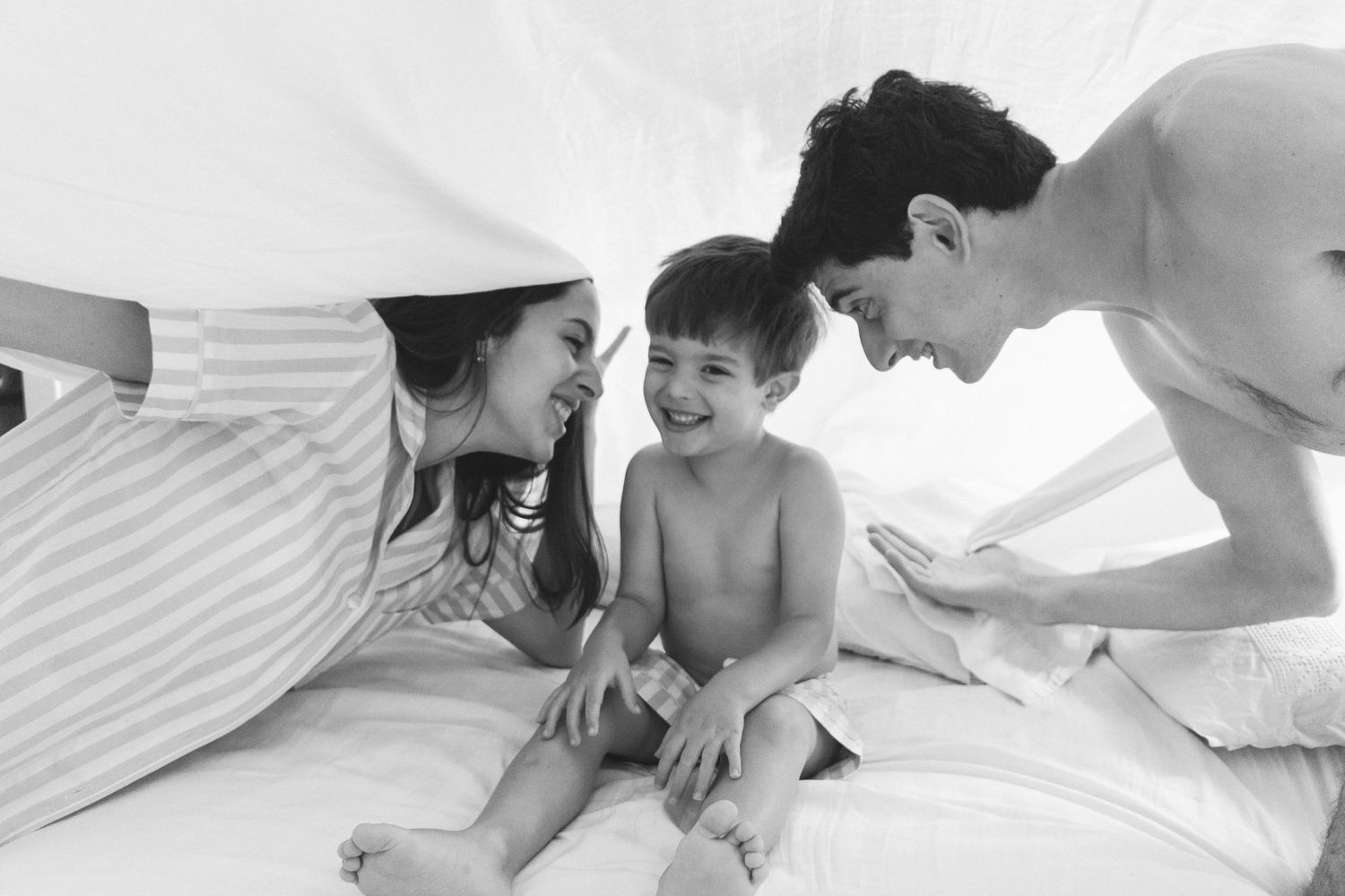 Family sharing a tender moment together under white sheets.