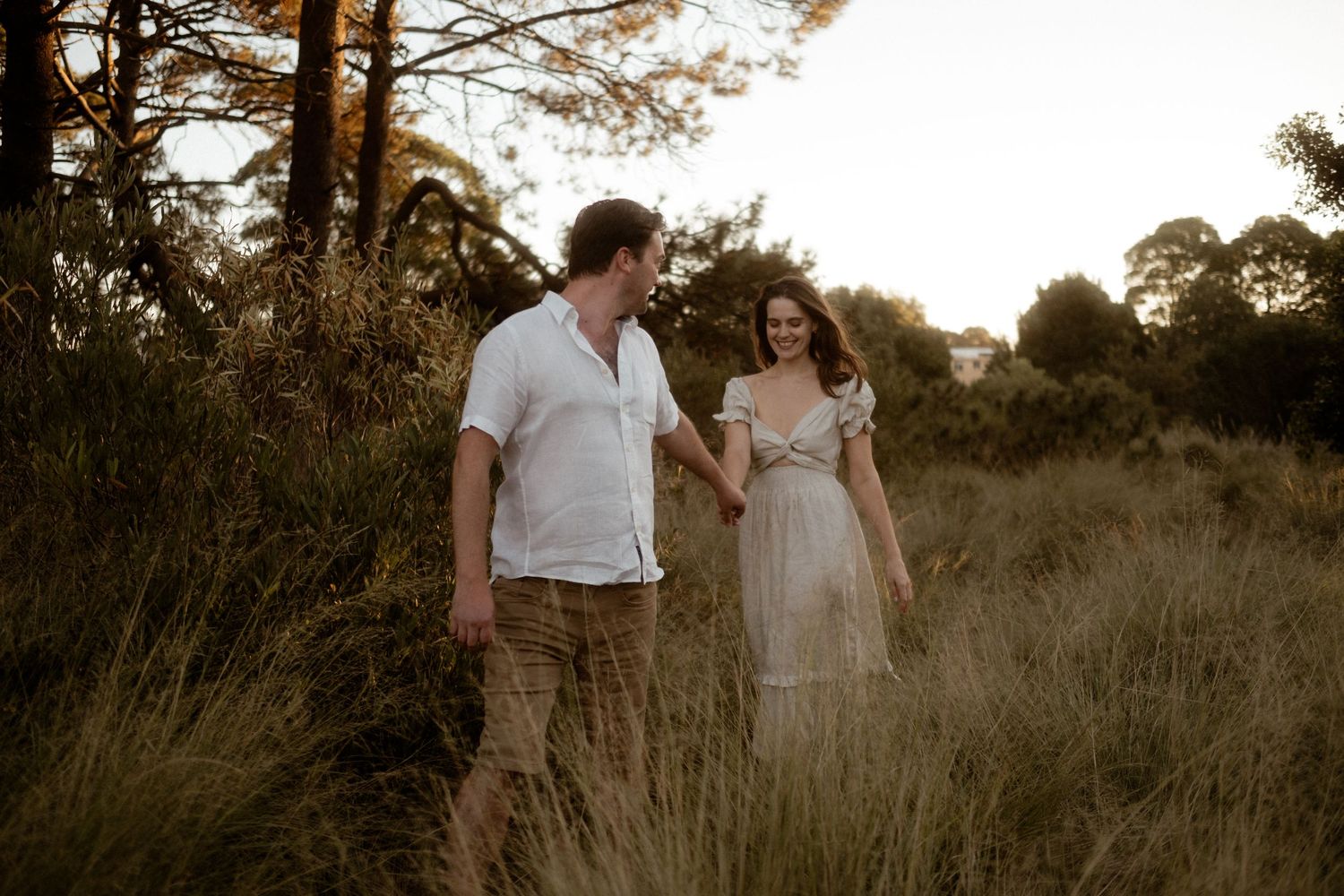 Intimate romantic moment captured in a sunlit meadow during golden hour.