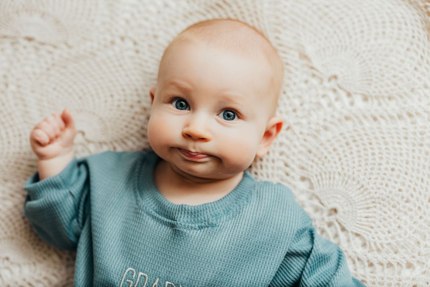 Close up portrait on white textured blanket wearing mint green sweater.