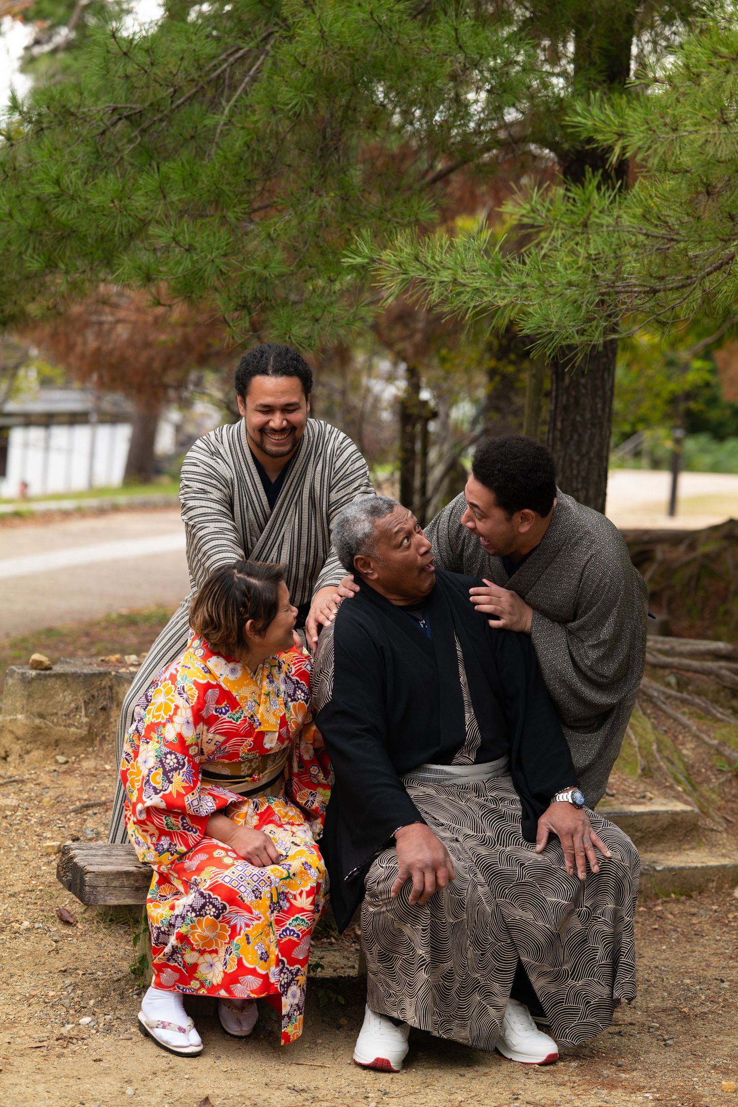 Family of four laughing together outdoors in traditional Japanese kimono attire.