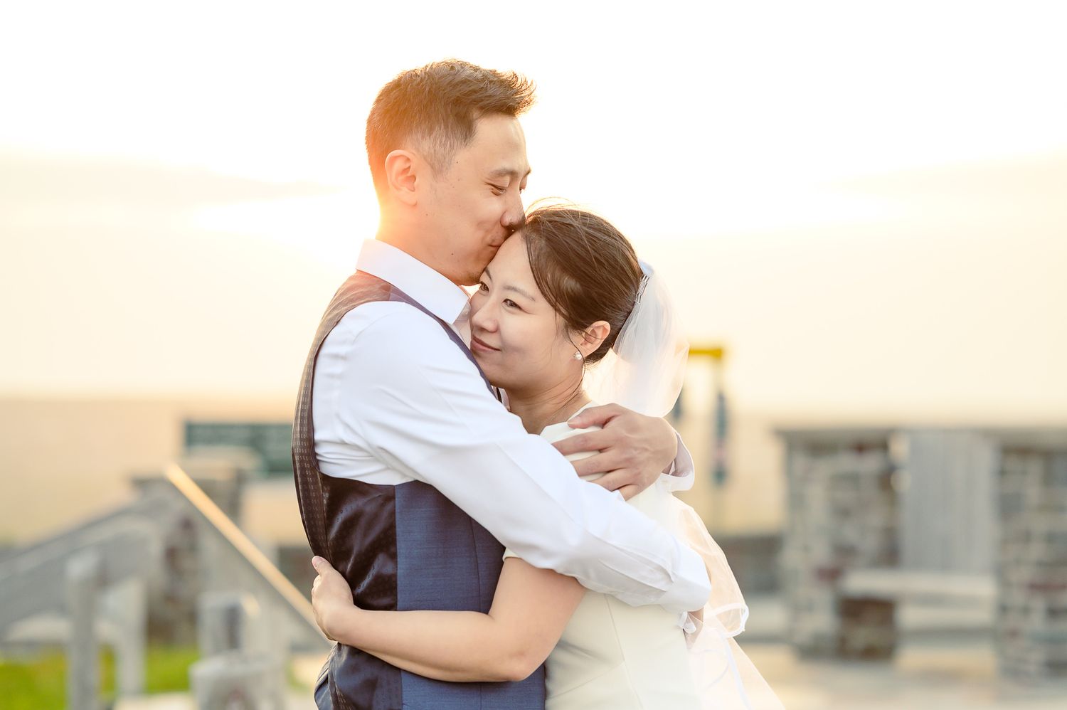 Bride standing with her back to the camera as the wind lifts her wedding dress during an outdoor portrait session.