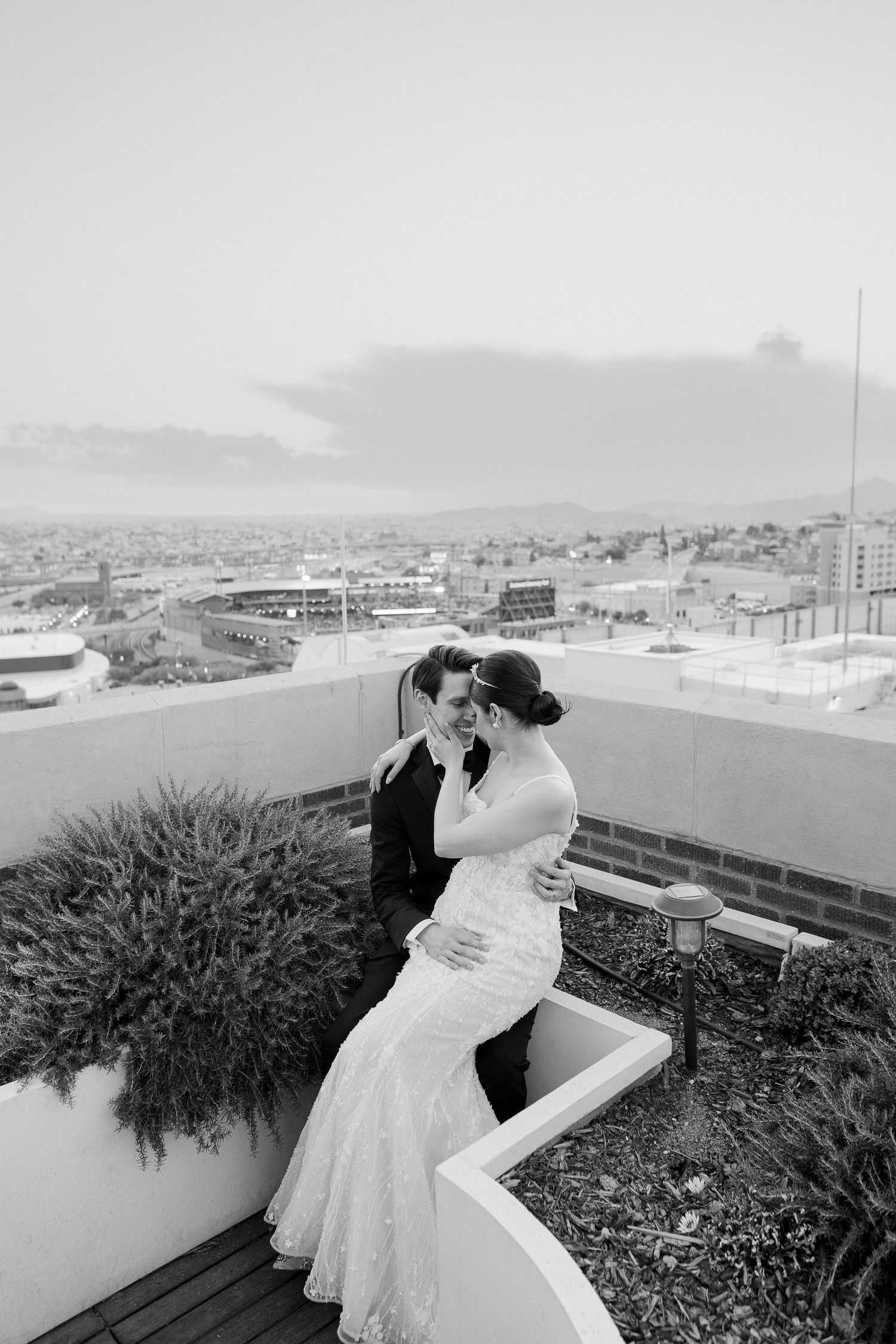 A romantic rooftop moment against a city skyline captured in a series of black and white wedding photographs.