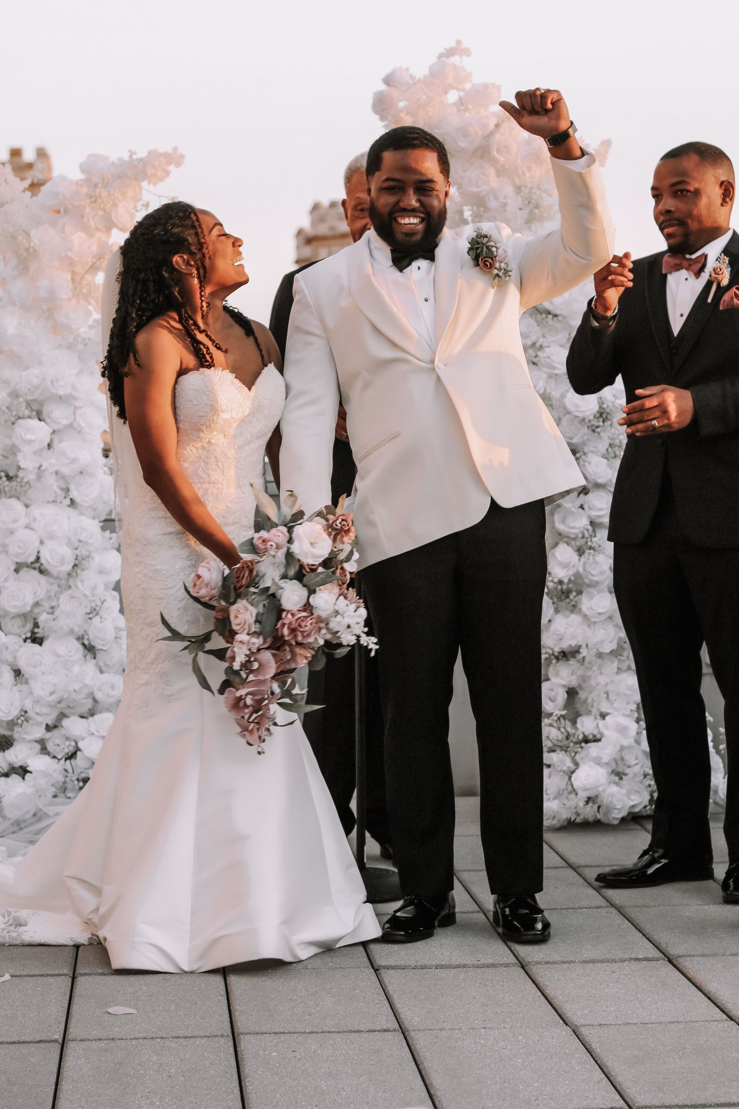 Wedding celebration with elegant white floral wall backdrop and joyful moment.