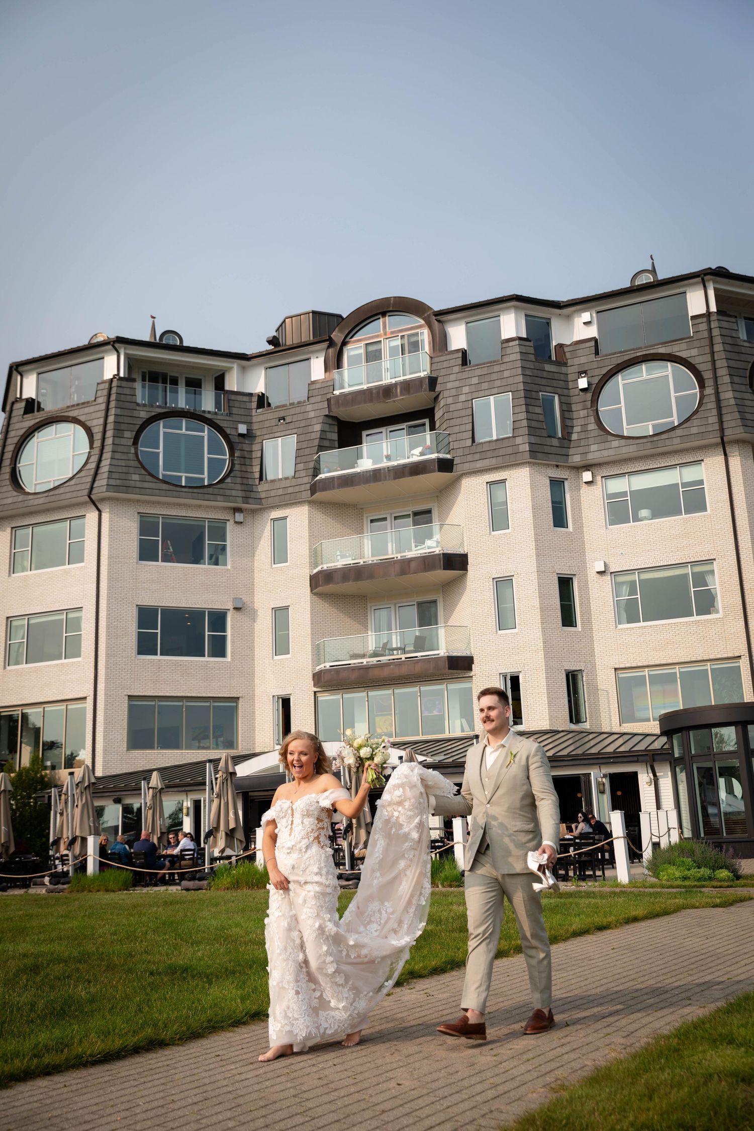 Bride and groom walk together with distinctive circular windows and contemporary architecture. Village of Bay Harbor wedding.