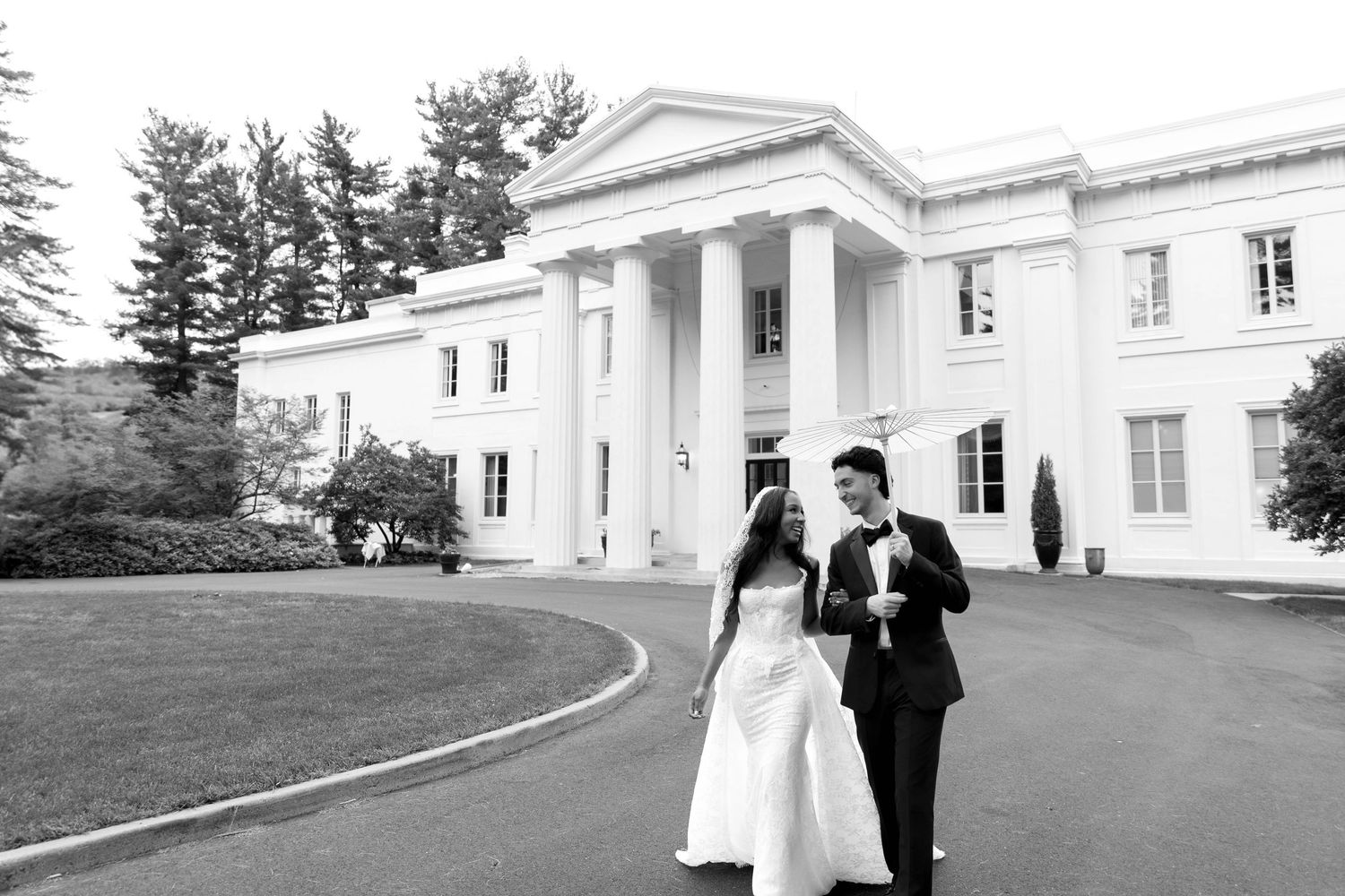 A black and white wedding photo series showing a couple walking outside a grand white columned building.