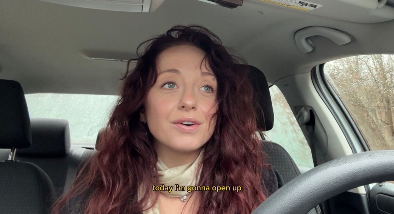 Someone with long red hair takes a series of selfies while sitting in the driver's seat of a car.