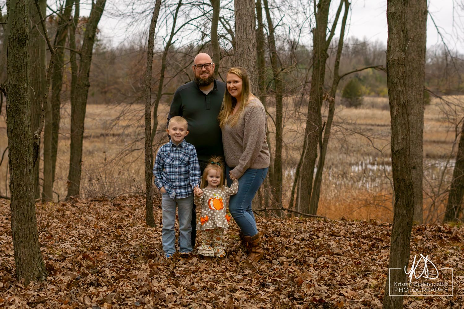 Family portrait in wooded area during fall with leaves on ground