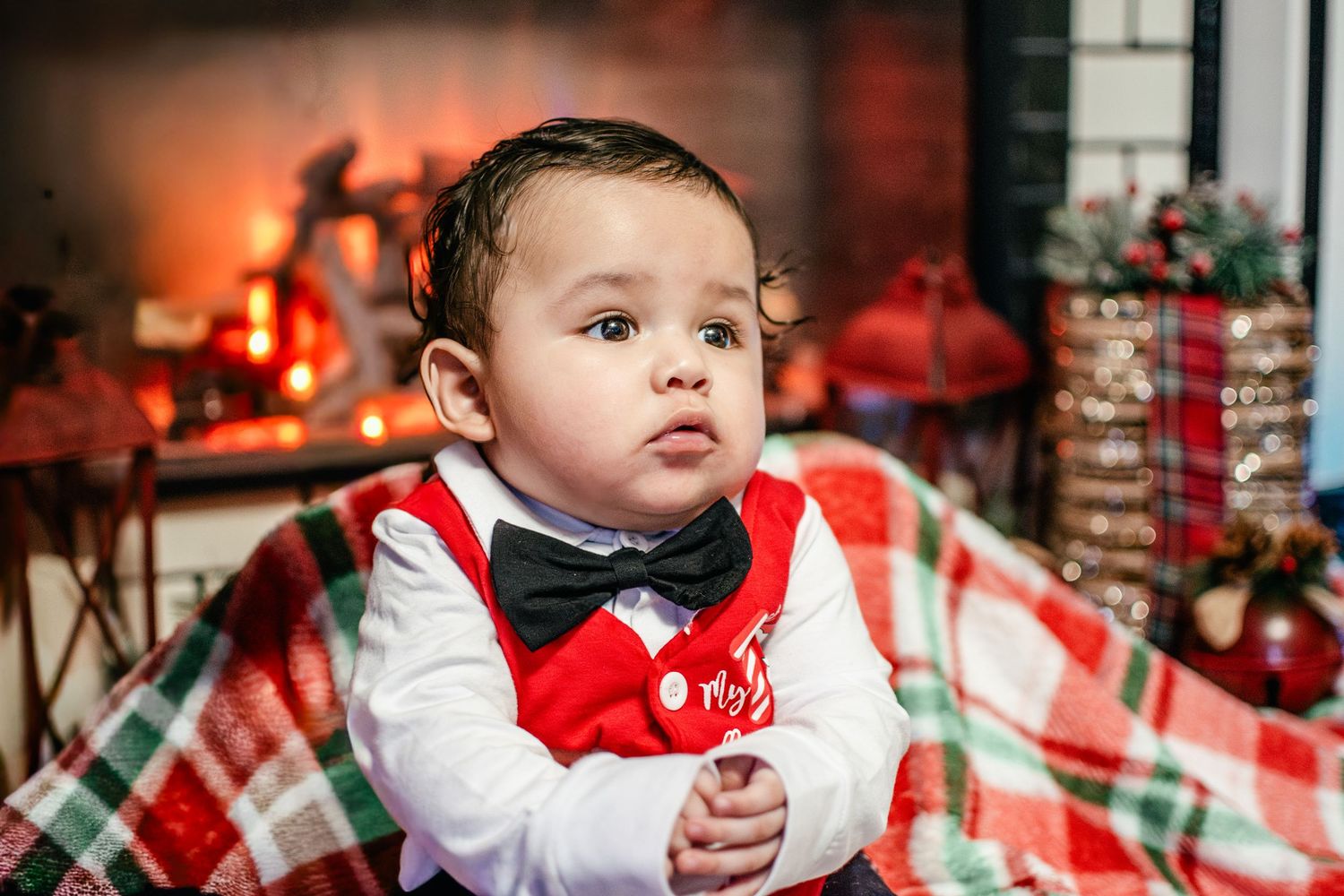 Four-month-old baby boy sitting by a fireplace during his first Christmas photo session in Puyallup, Washington