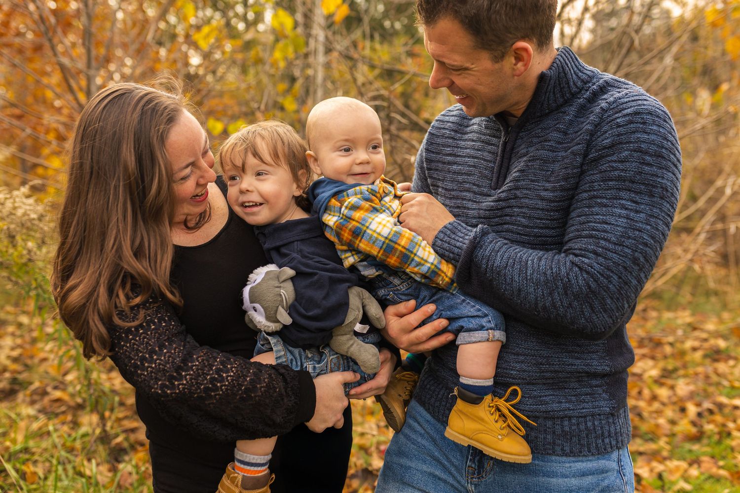 A group of people embracing and laughing together outdoors during autumn with fallen leaves in the background.