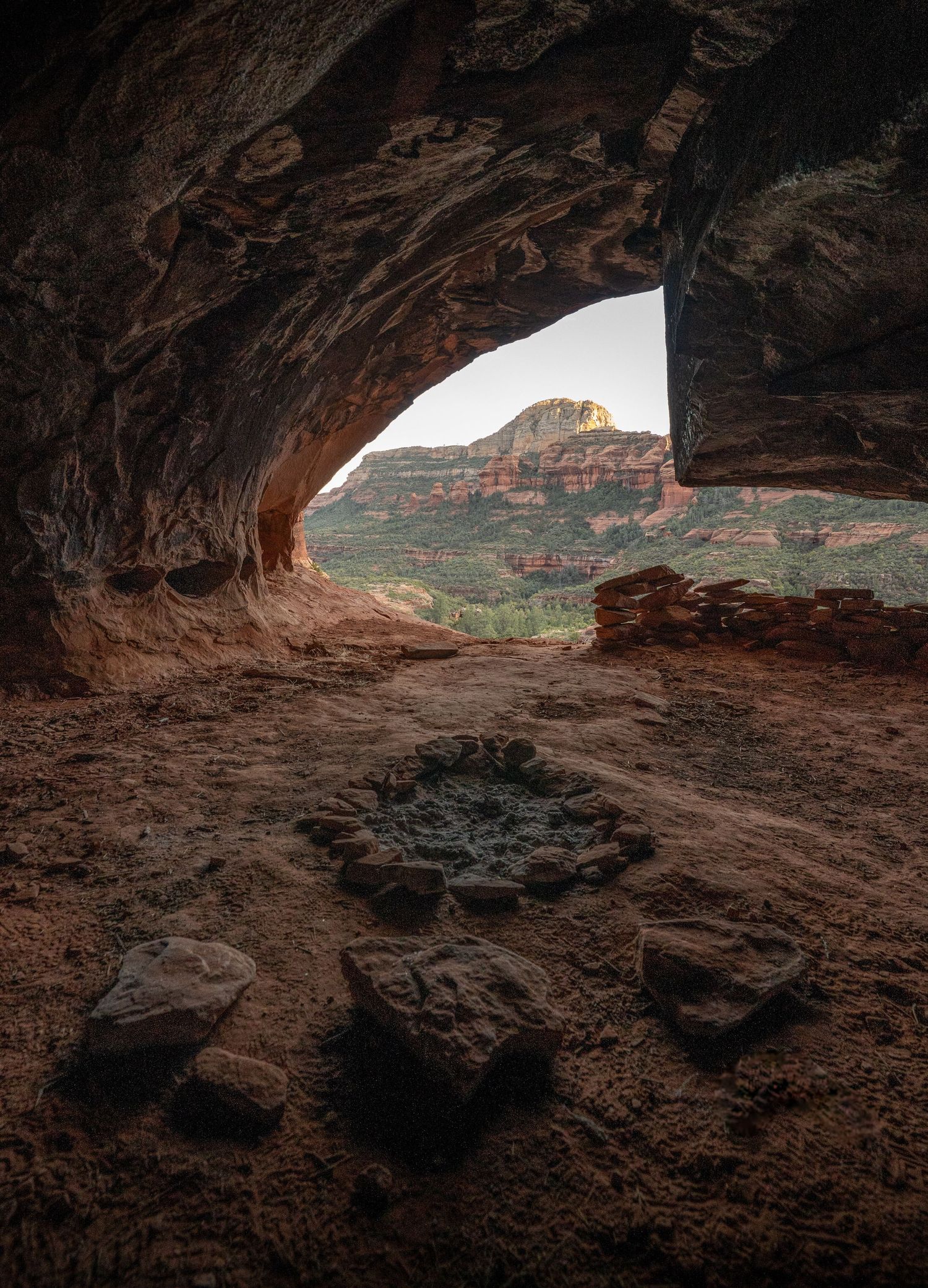 A dramatic series of cave openings in red rock formations show natural arches framing distant desert landscapes.