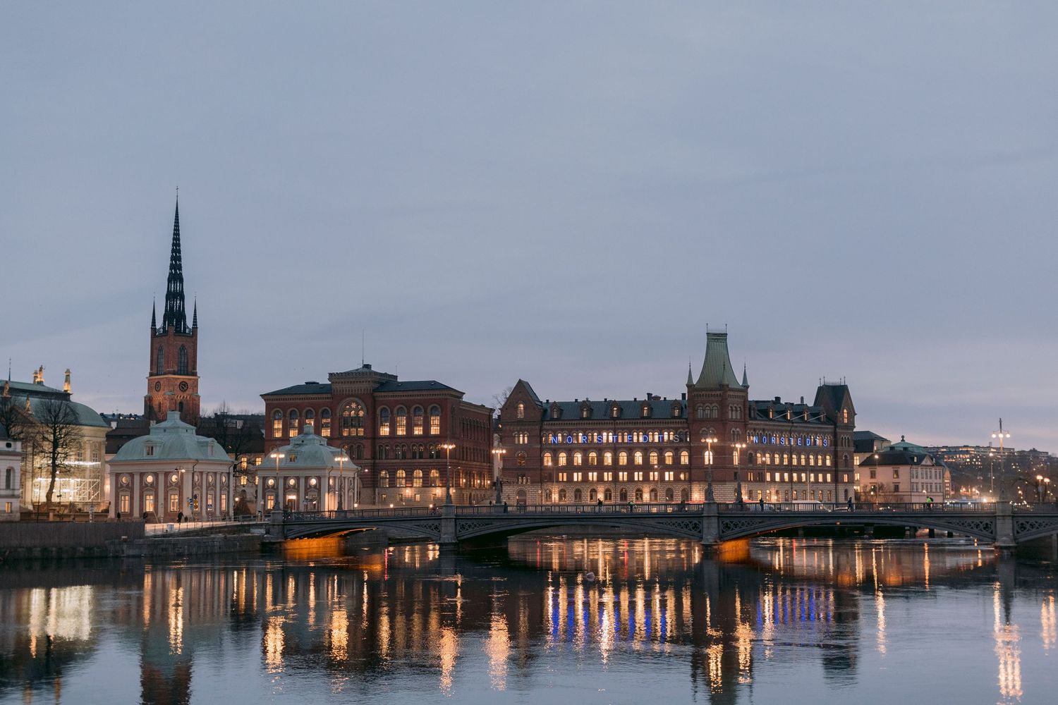 Stockholm historic Gamla Stan skyline reflected in water during blue hour evening light.