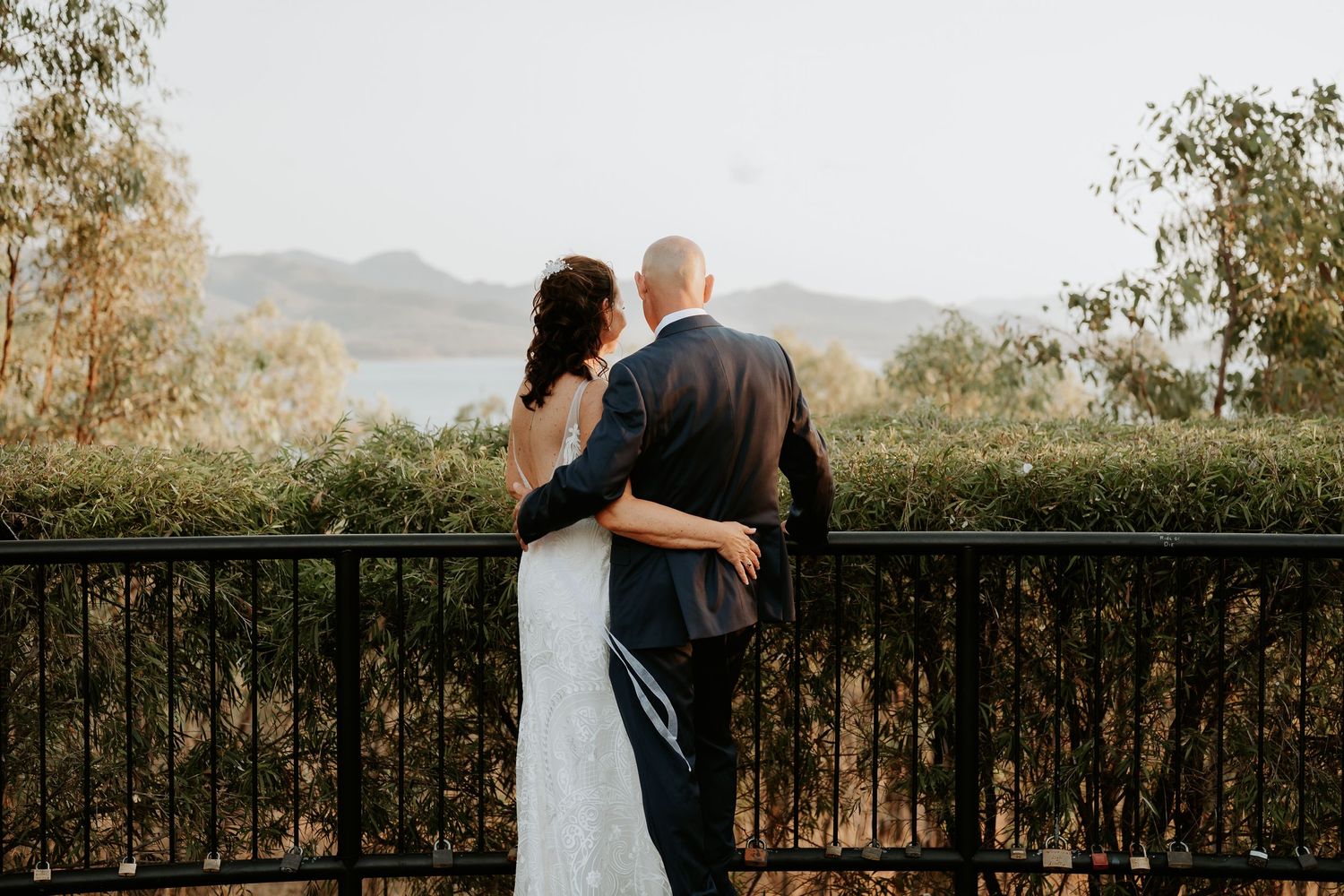 Couple embraces while enjoying scenic mountain views from a rustic balcony railing at sunset.