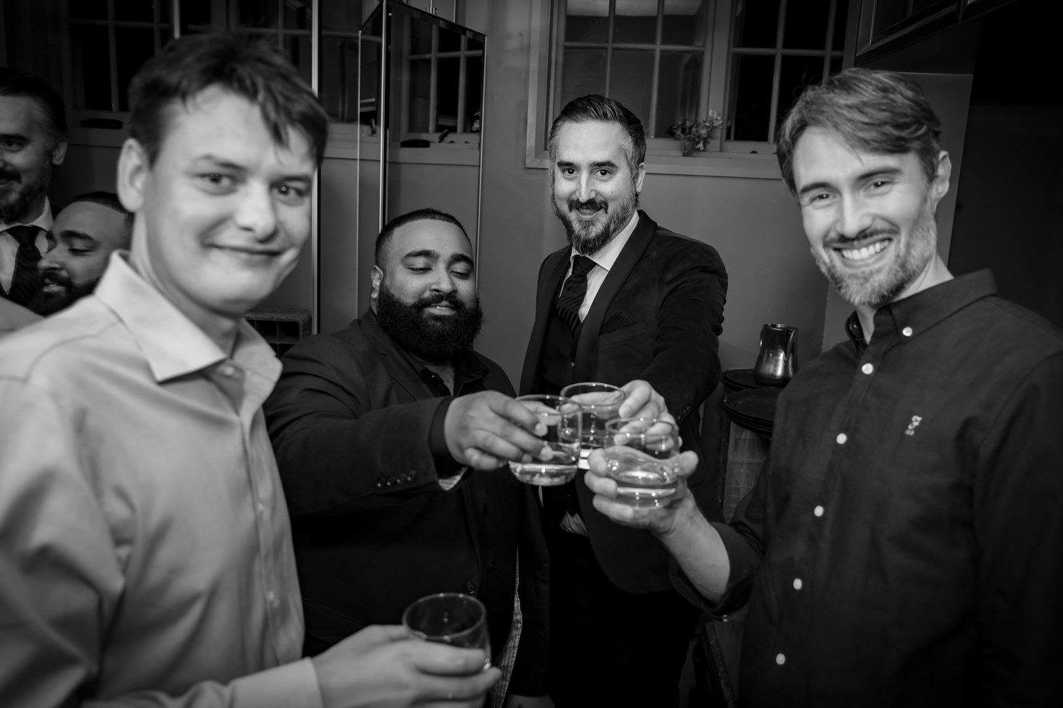 A black and white photo of several men holding drinks at a celebration gathering.