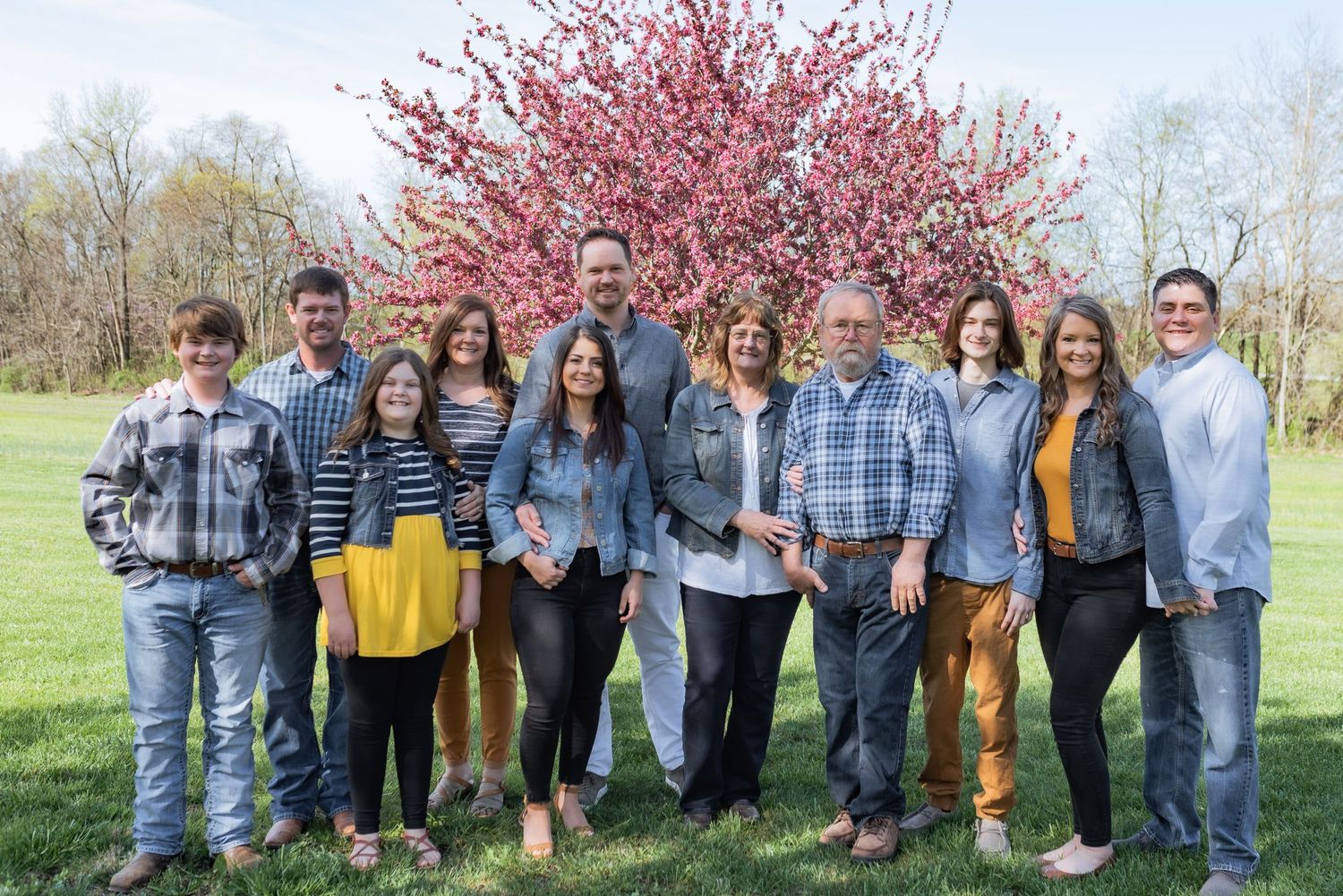Group photo outdoors with pink cherry blossom tree in spring background.