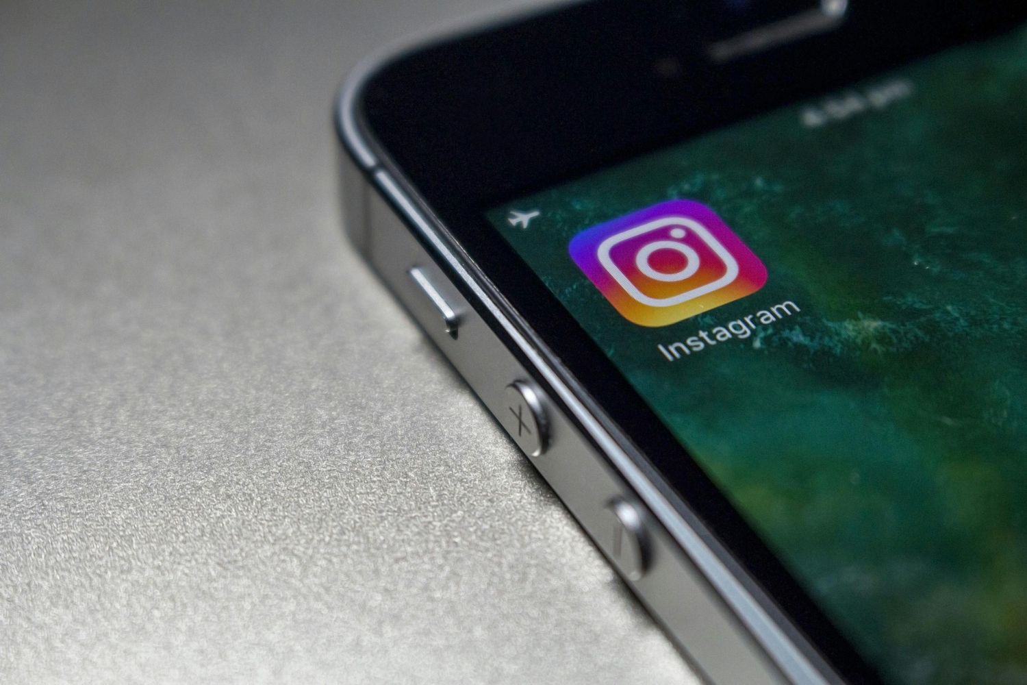 Instagram app icon displayed on a dark screen of a silver smartphone against a gray background.