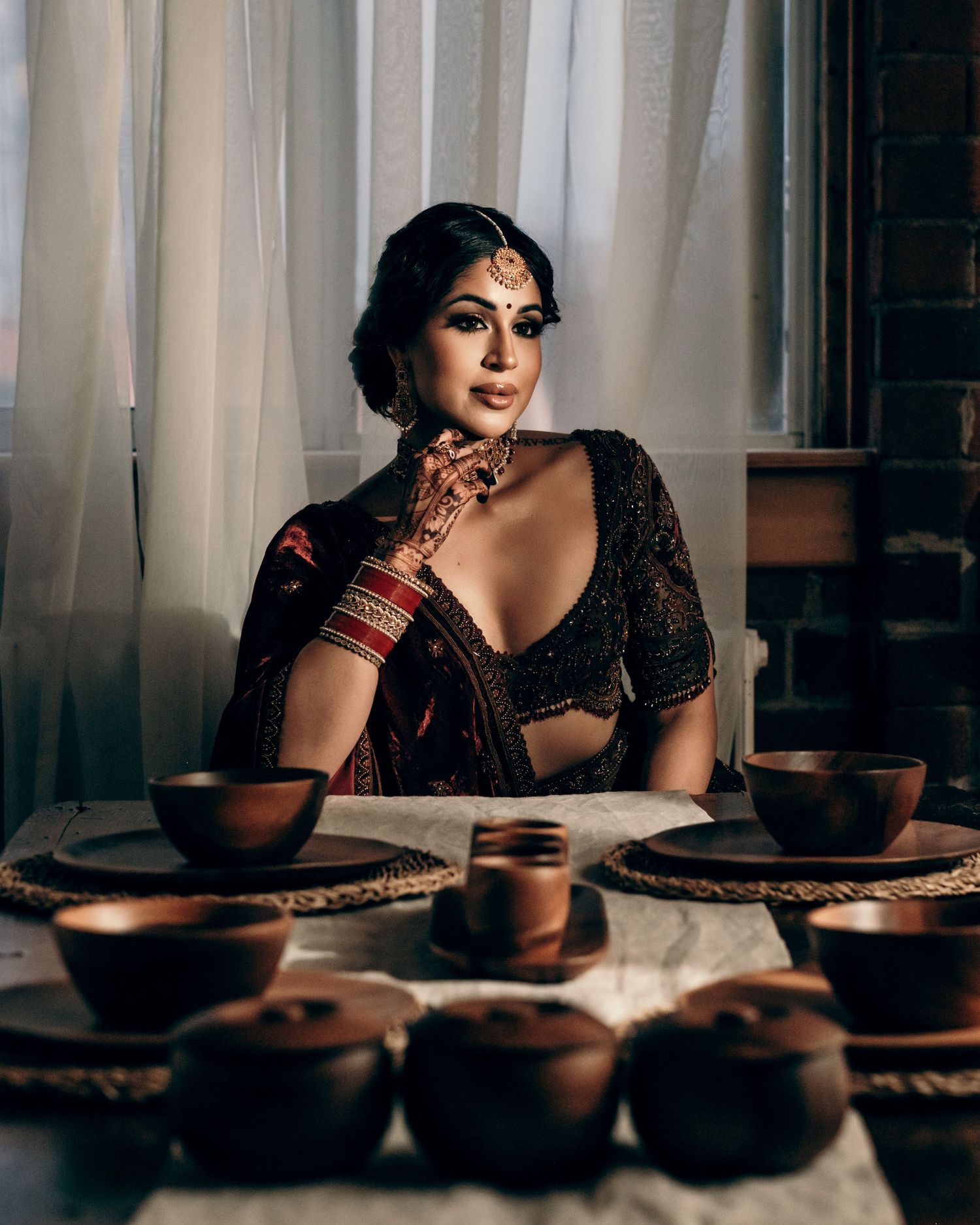 Traditional Indian earthenware pottery and clay cups arranged on table with person in elegant embroidered attire.