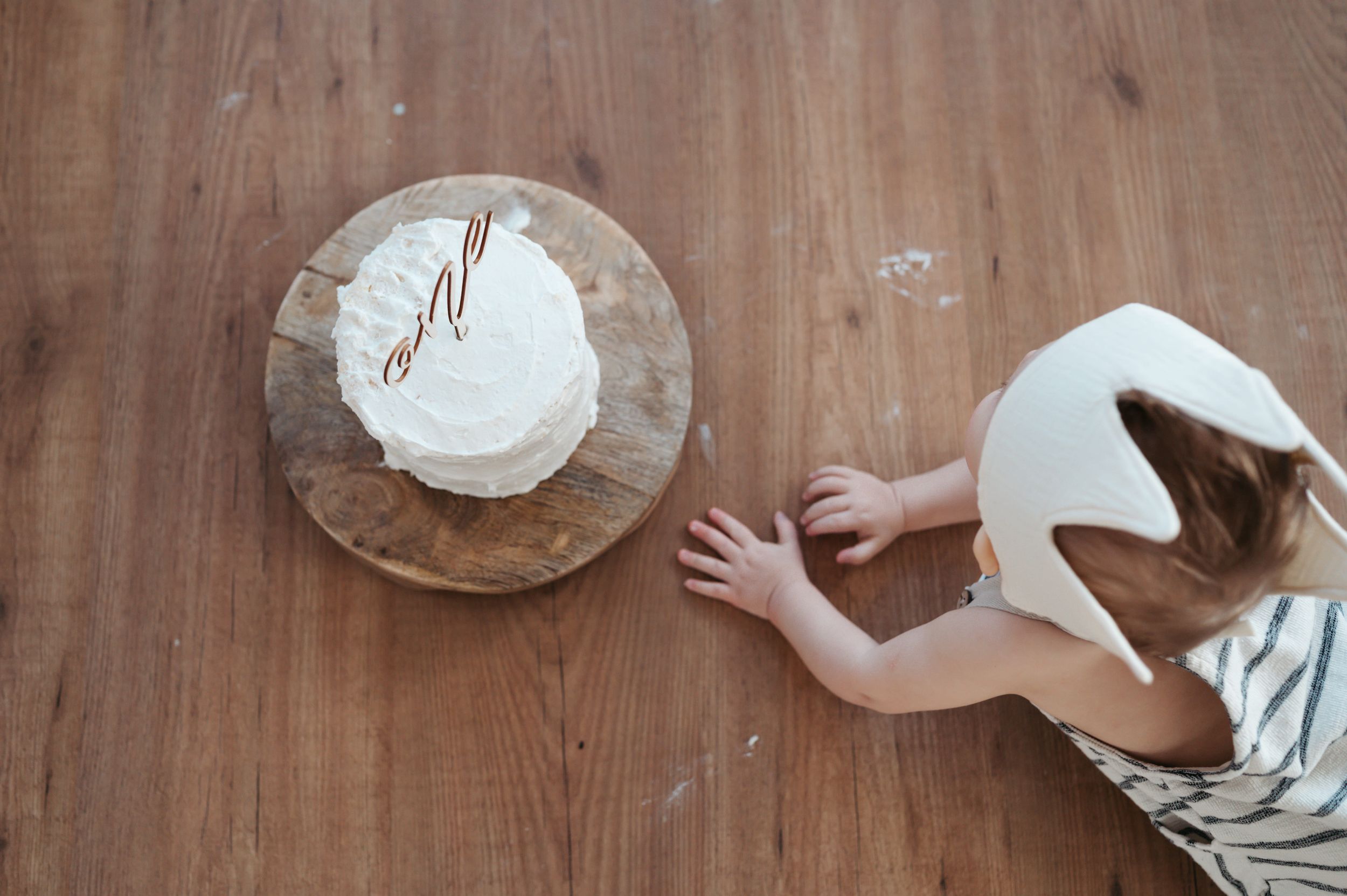 Baby tijdens caksemash fotoshoot die naar de taart rijkt van bovenaf gezien. 12 leukste cadeautjes kindje 1 jaar. 
Eerste verjaardag