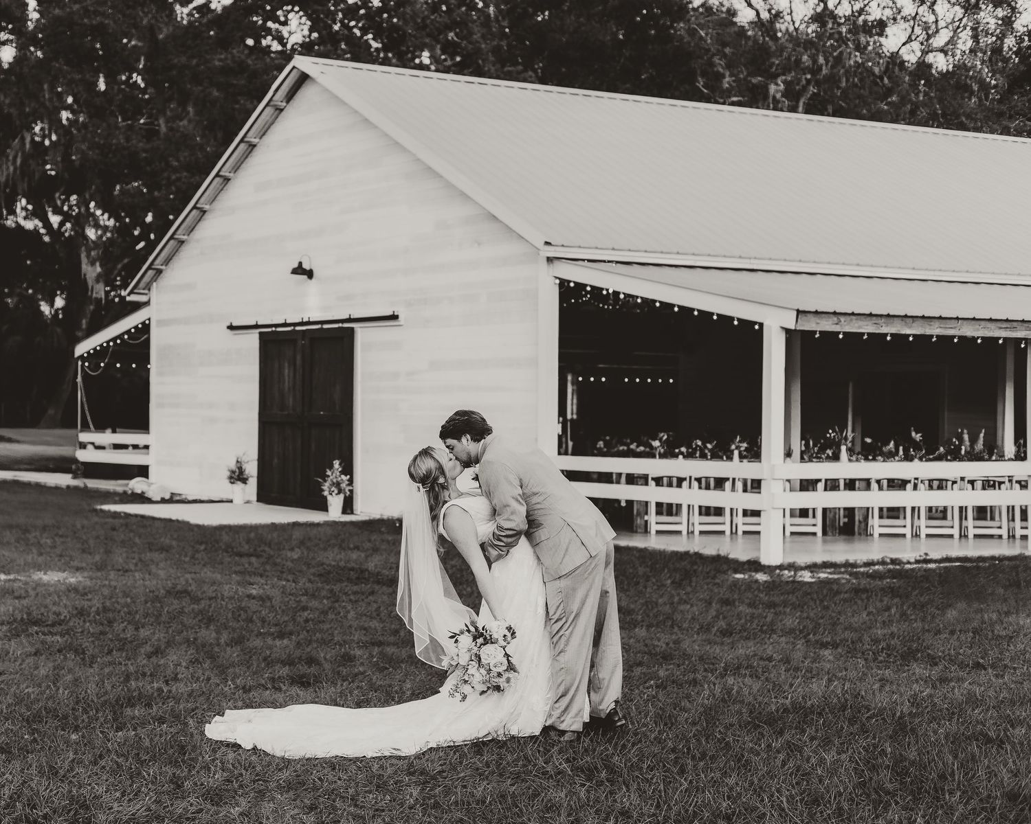 Black and white wedding photos taken on a grassy field with white chairs in the background.