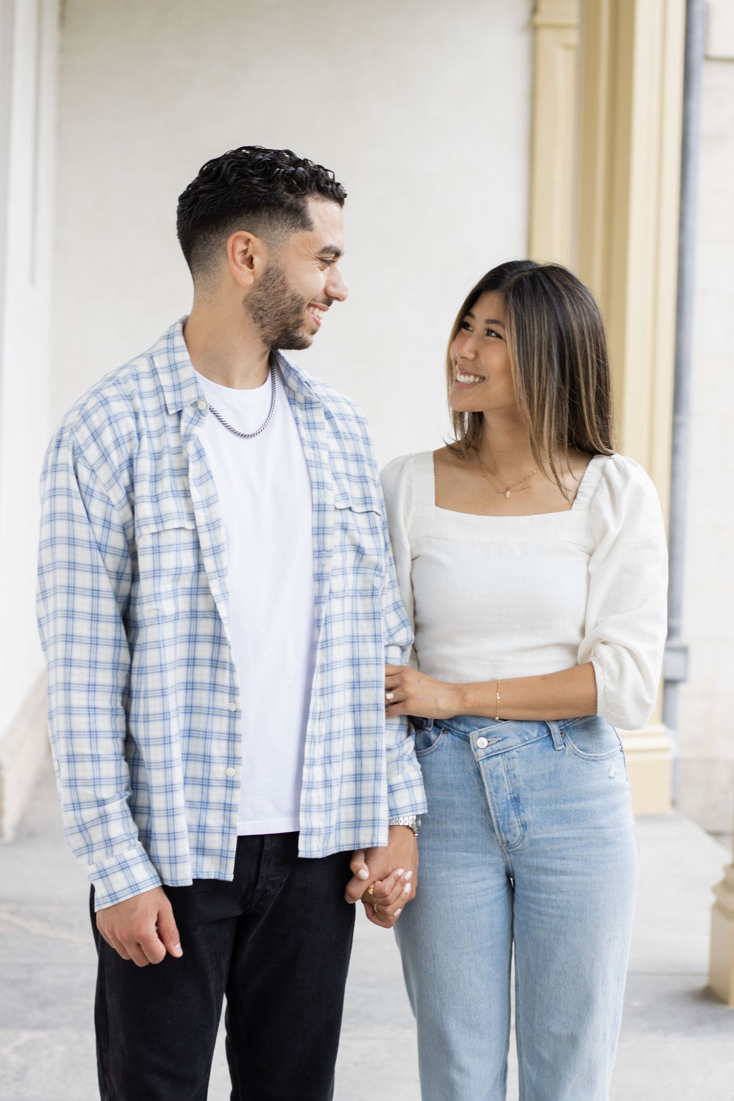 A person wearing a white shirt and blue jeans rests their hand on blue plaid fabric.