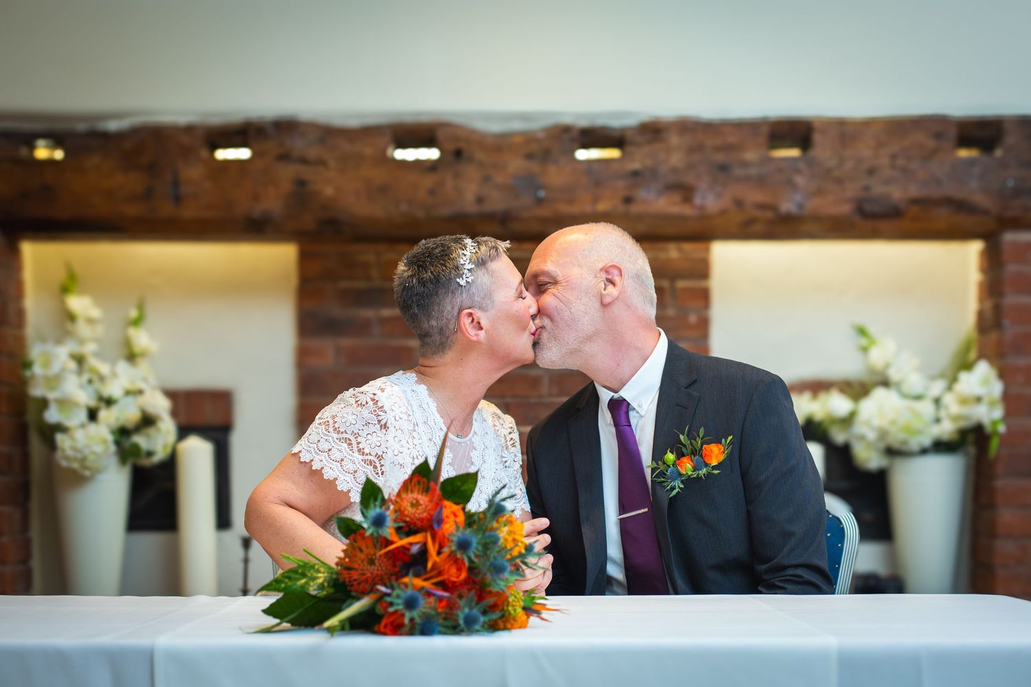Couple signing wedding documents at a ceremony with floral decorations.