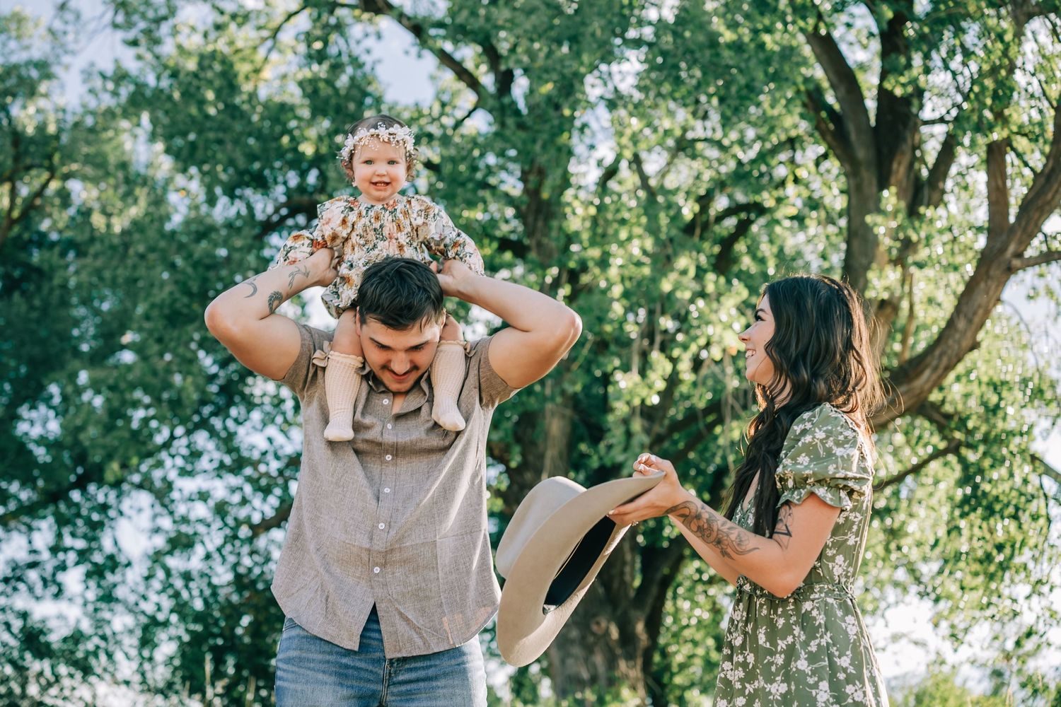 A playful family moment captured in a sun-dappled outdoor setting.