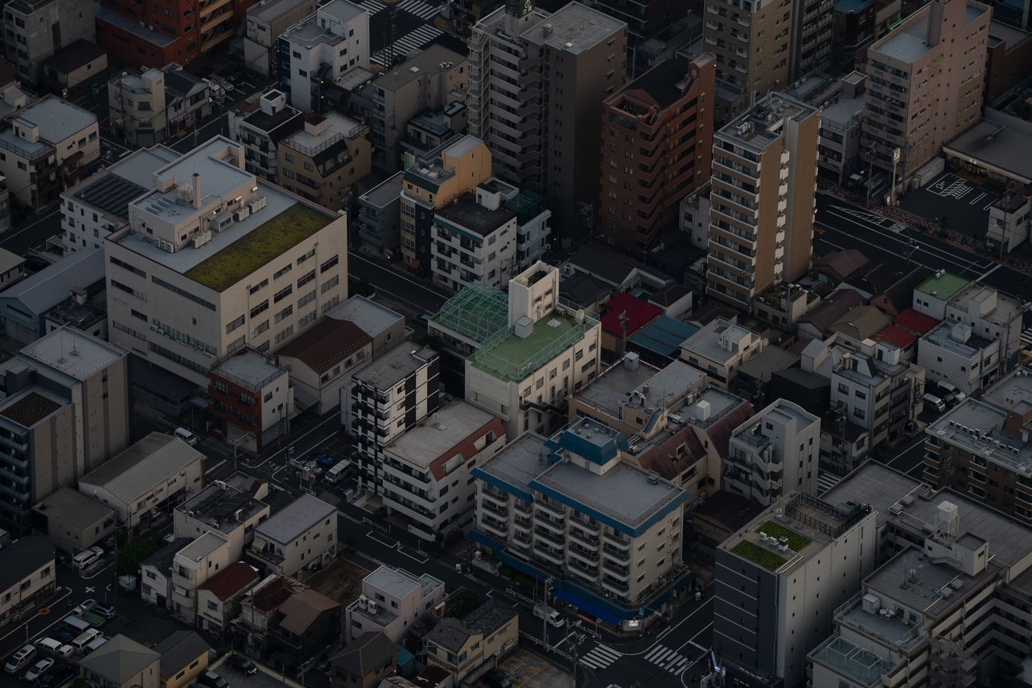 Aerial view of dense urban buildings and architecture in a cityscape at dusk.
